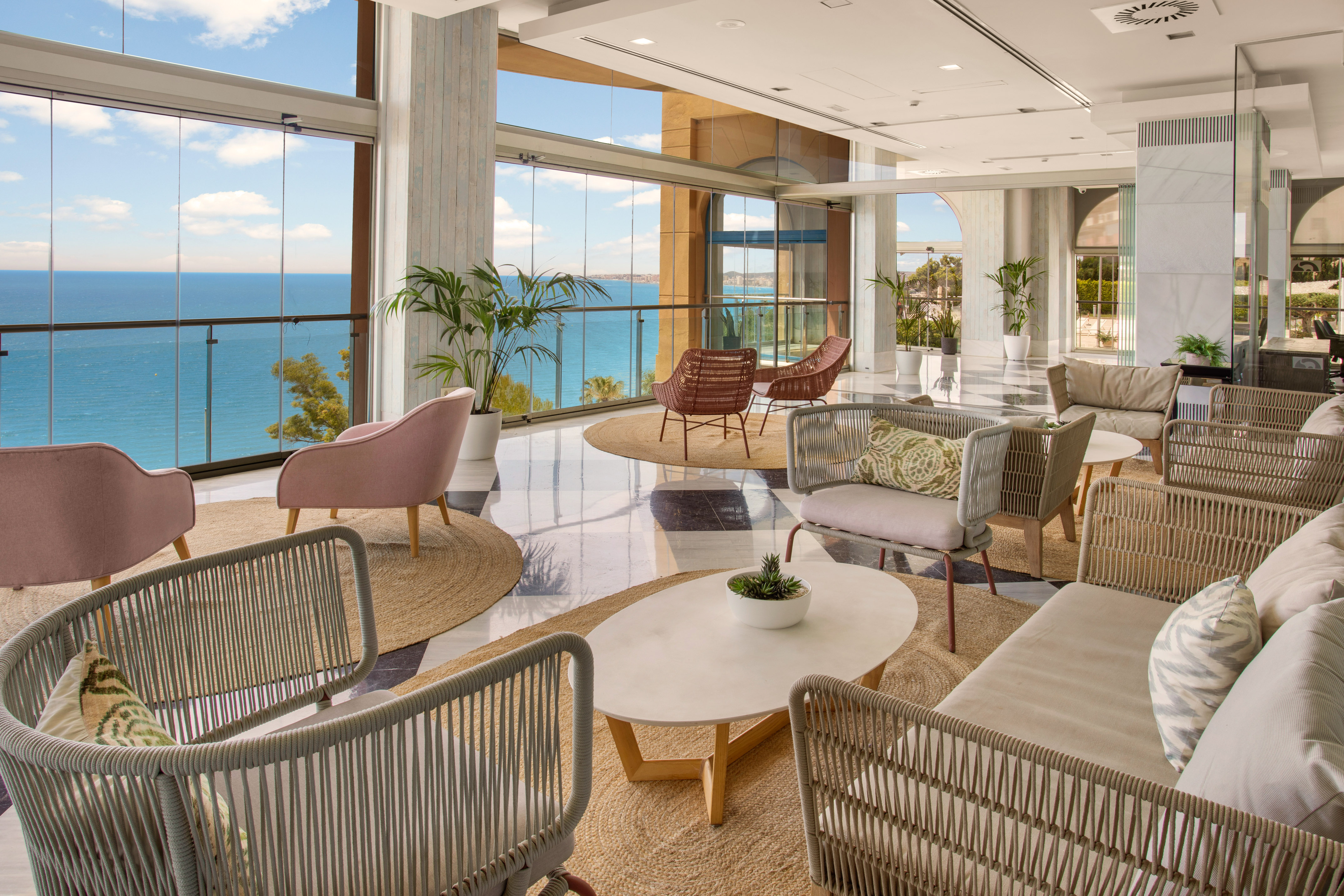 Modern hotel lounge with panoramic sea view, stylish seating, and natural light.