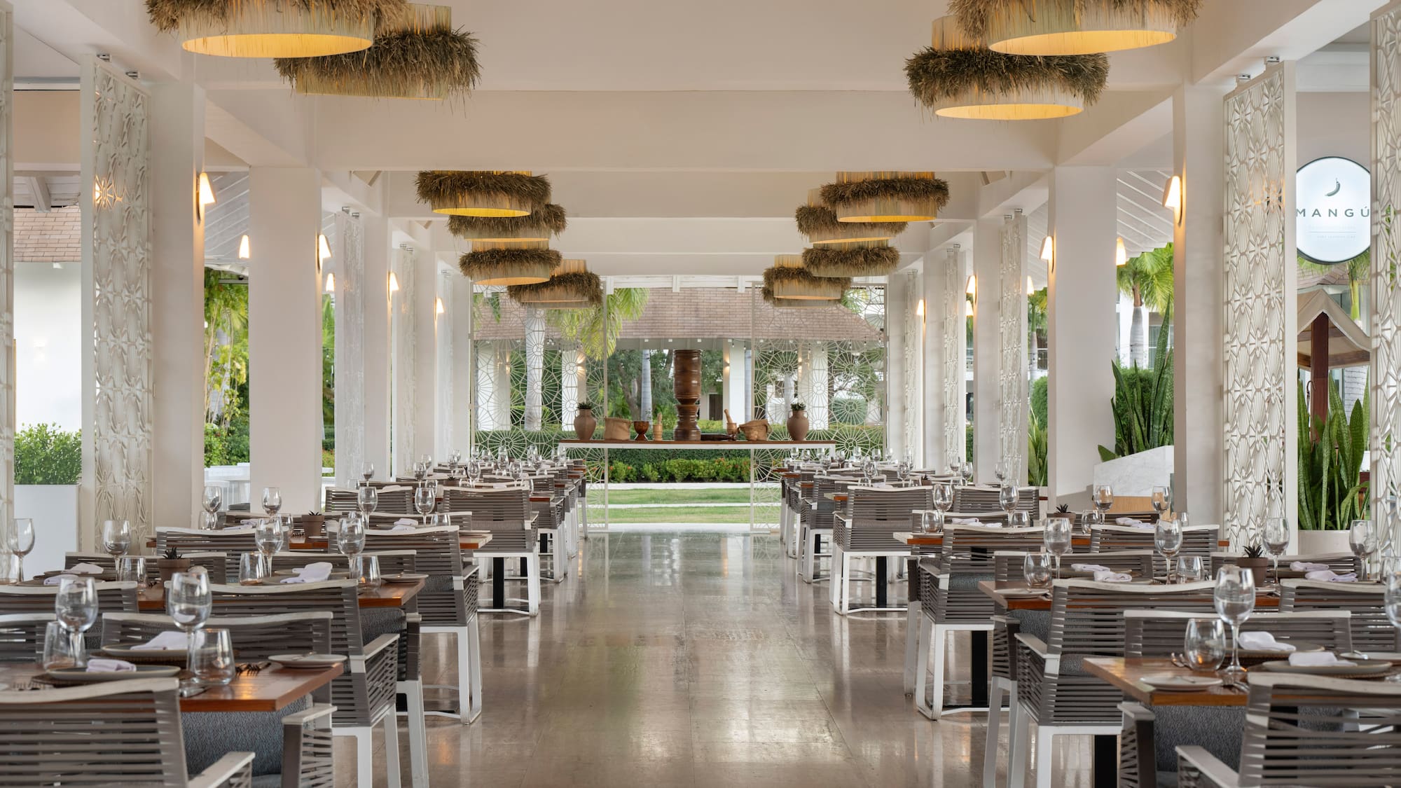Mangu tropical restaurant dining room, modern decor, set tables, straw chandeliers.