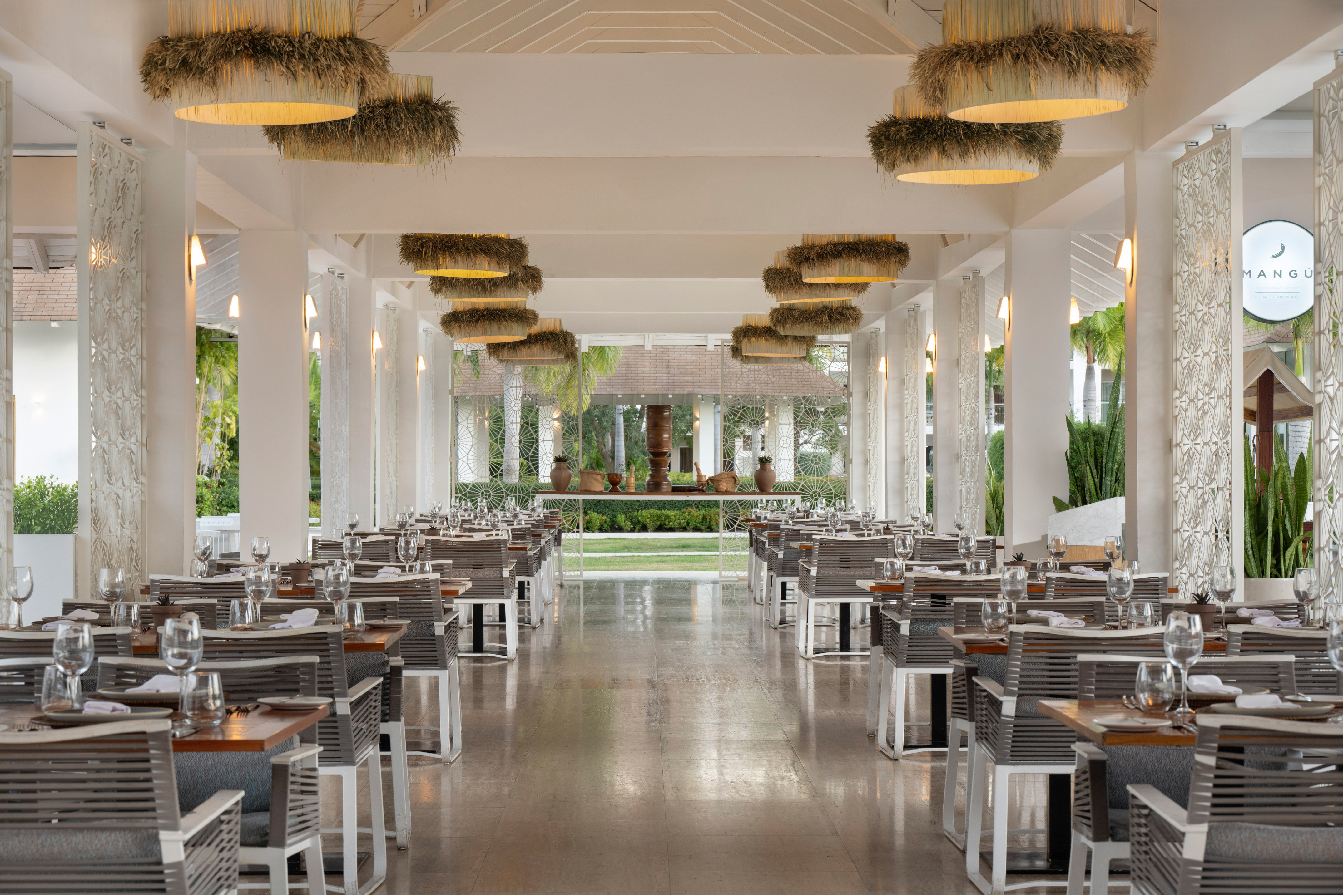 Mangu tropical restaurant dining room, modern decor, set tables, straw chandeliers.