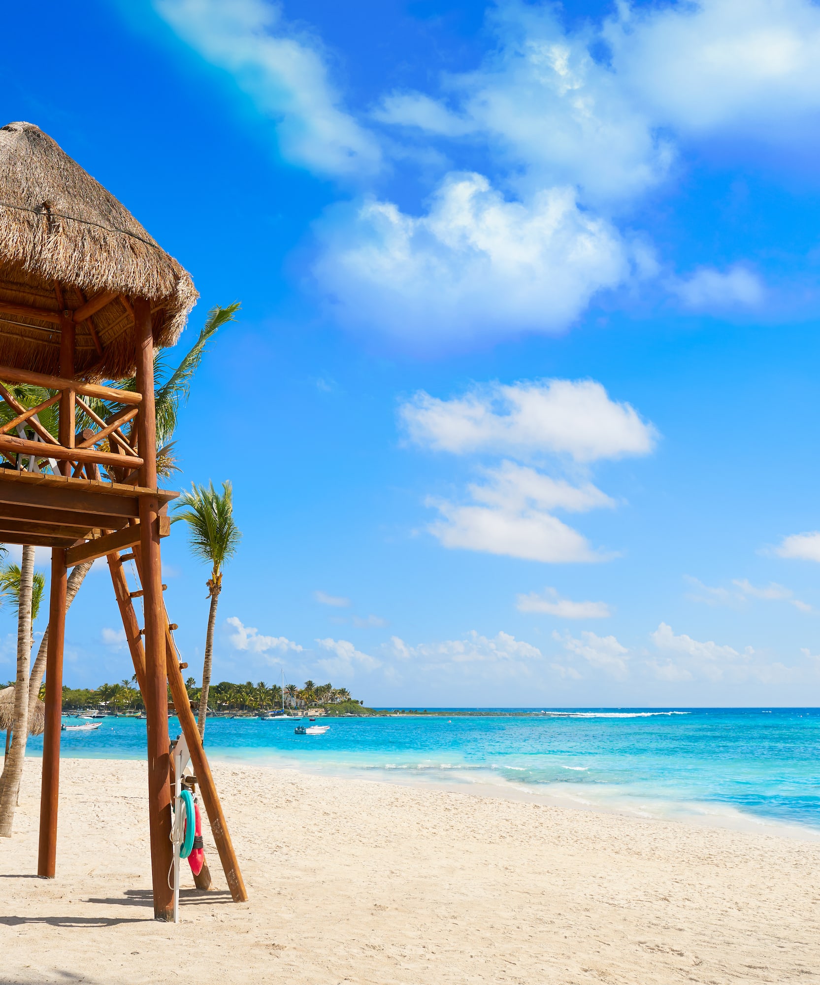 Playa caribeña con torre salvavidas, arena blanca, mar turquesa y palmeras.