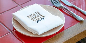 a plate with napkin and silverware on a red tile table