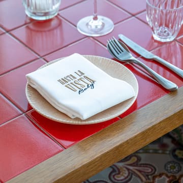 a plate with napkin and silverware on a red tile table