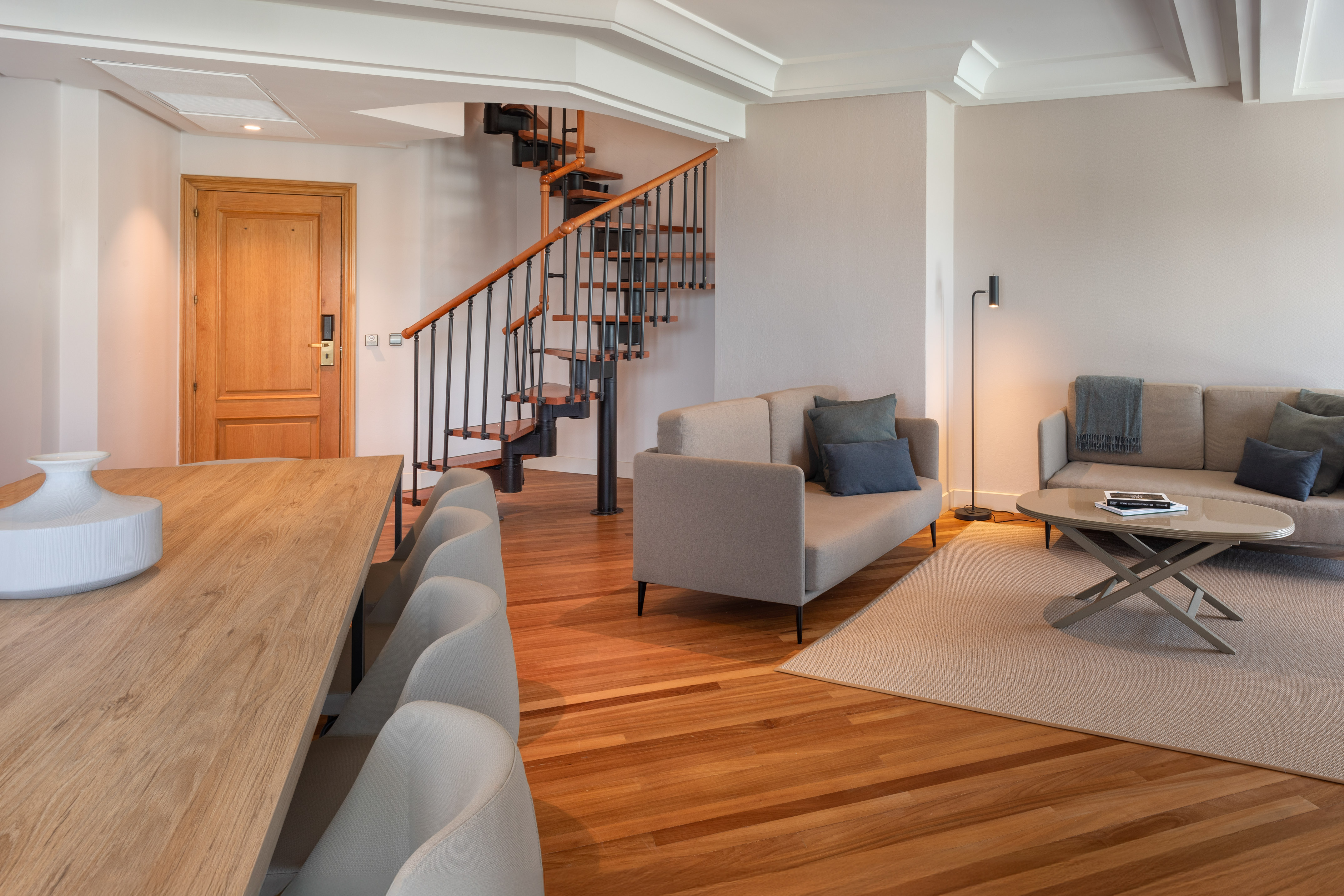 Contemporary open-plan living and dining room with spiral staircase, hardwood floor.