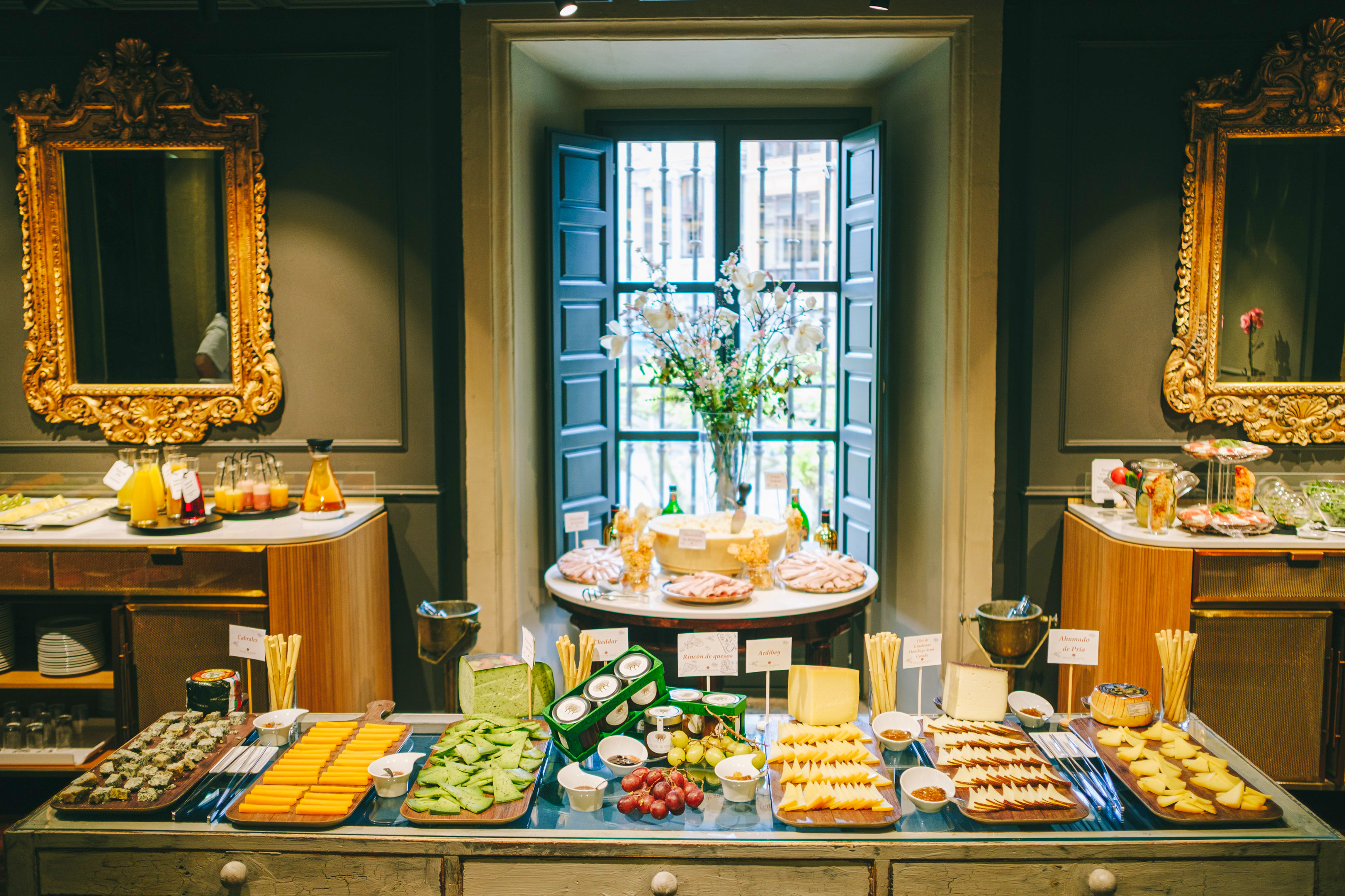 Cheese, cold cuts, and fruit buffet with juices in an elegant room setting. - La Capilla - Palacio de Avilés Afiliat Meliá, Avilés