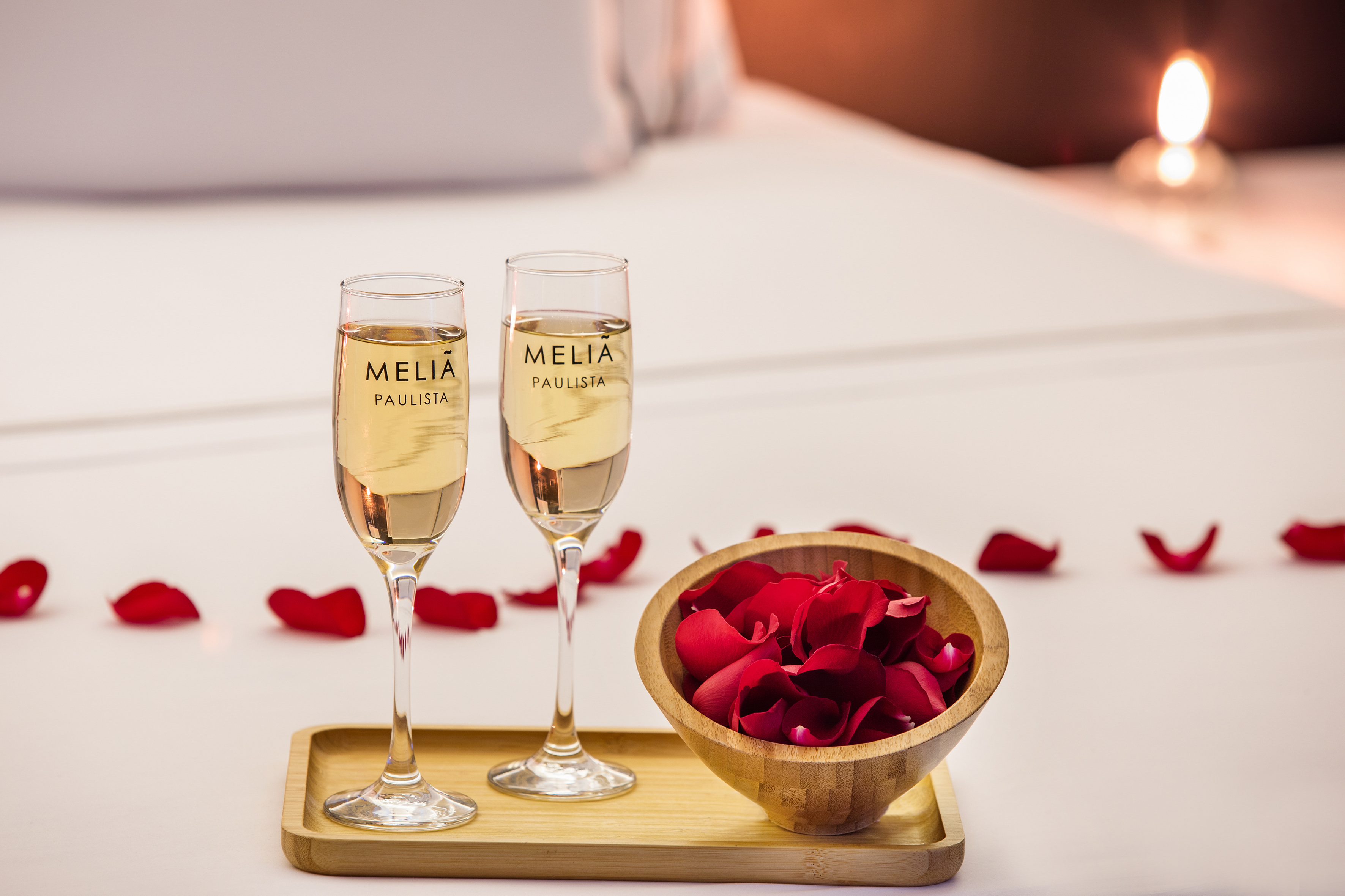 two glasses of champagne next to a bowl of rose petals