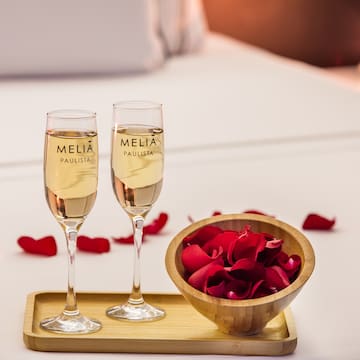 two glasses of champagne next to a bowl of rose petals