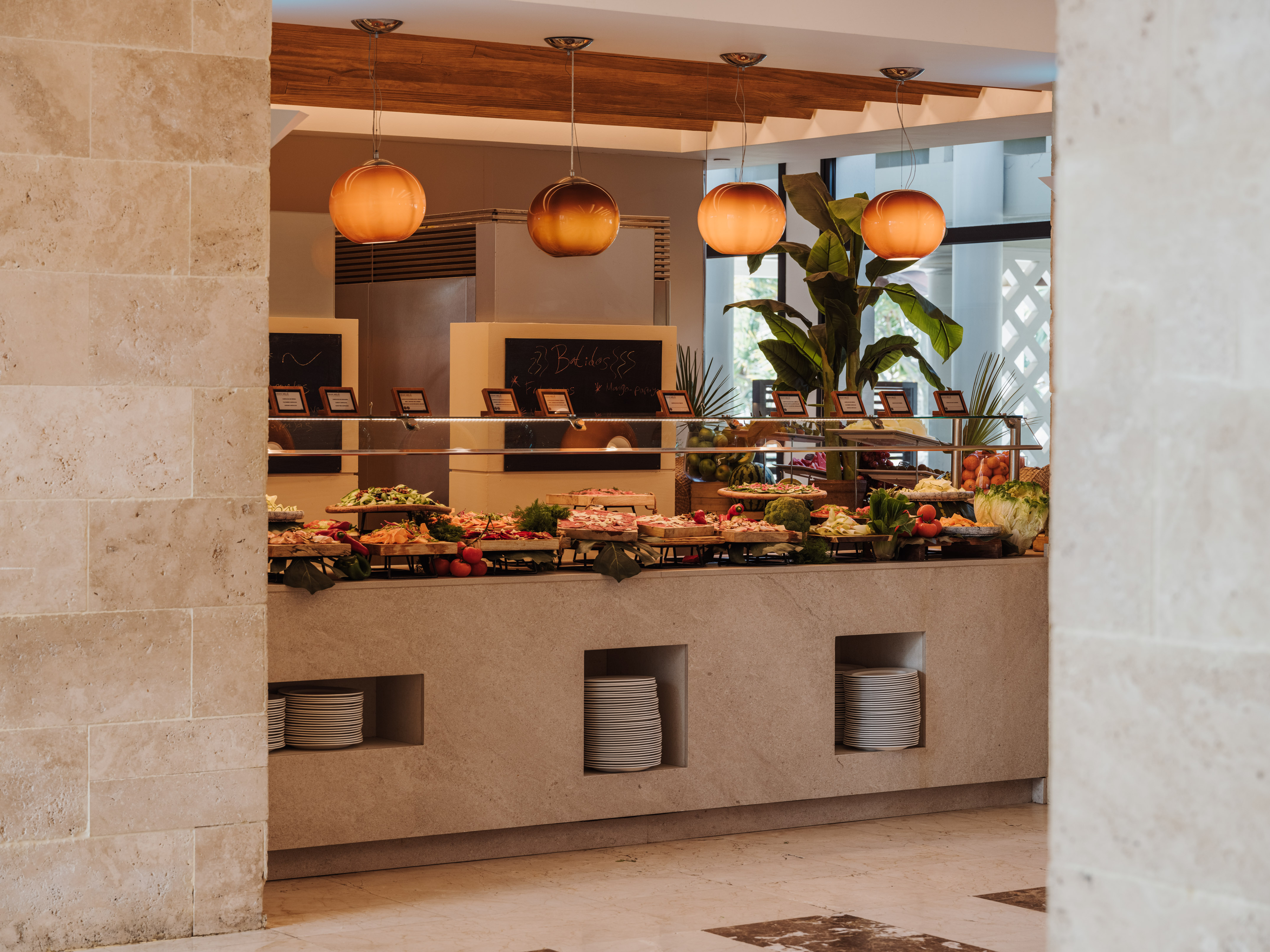 Modern hotel restaurant buffet with fresh salads, fruits, and diverse dishes.