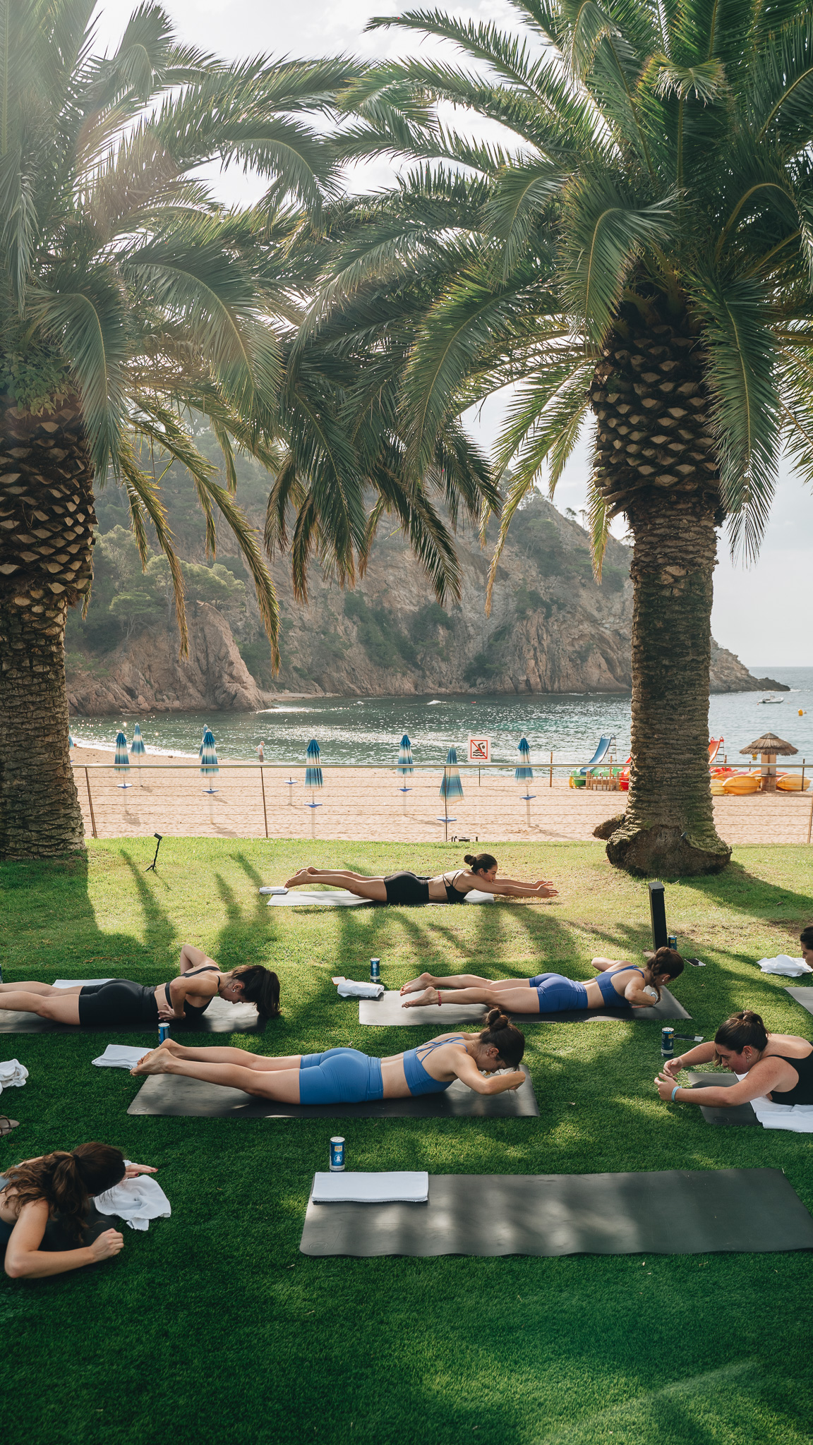a group of people lying on mats on grass next to palm trees