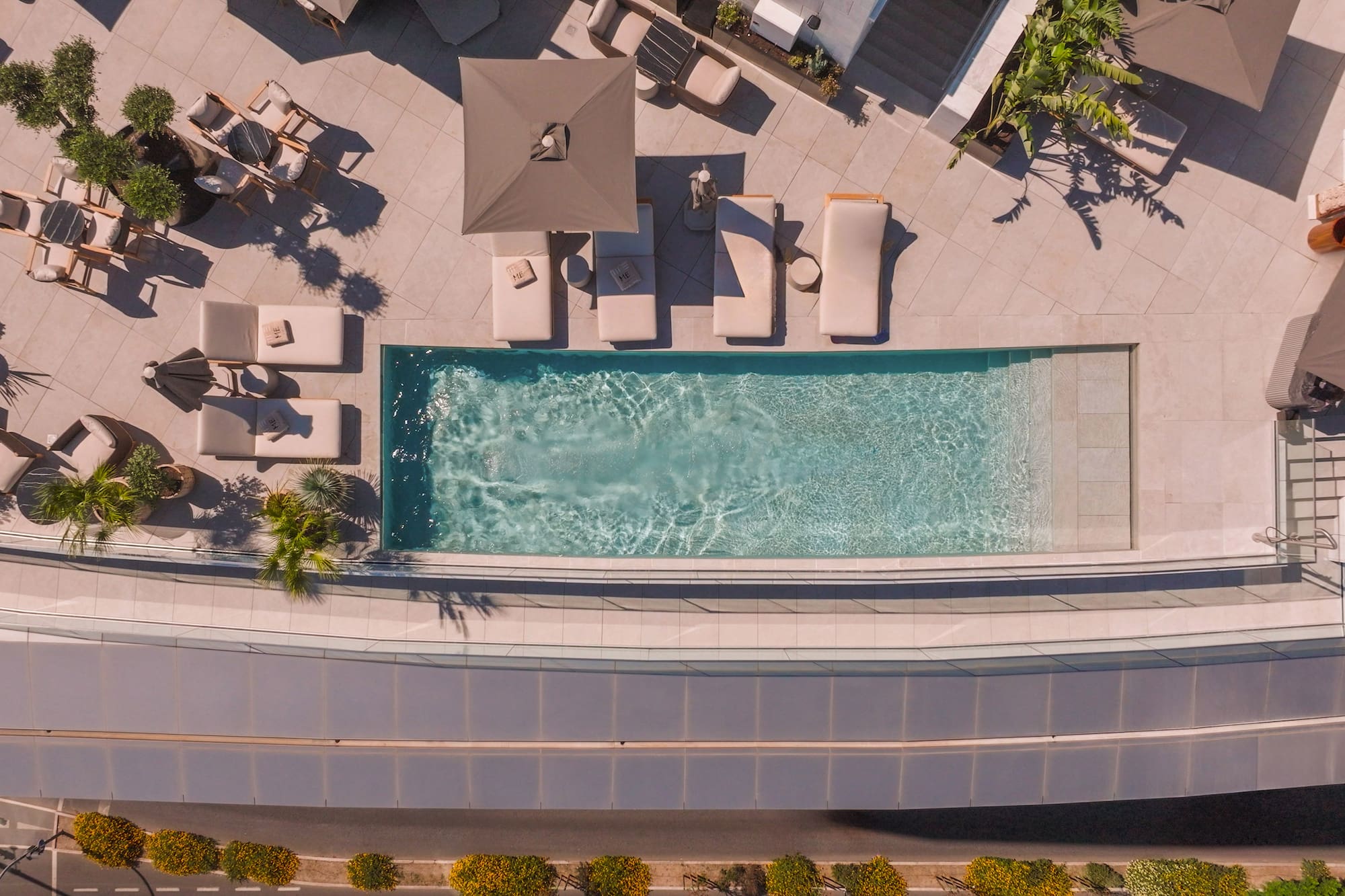 Luxury hotel rooftop pool and terrace with sunbeds and umbrellas.