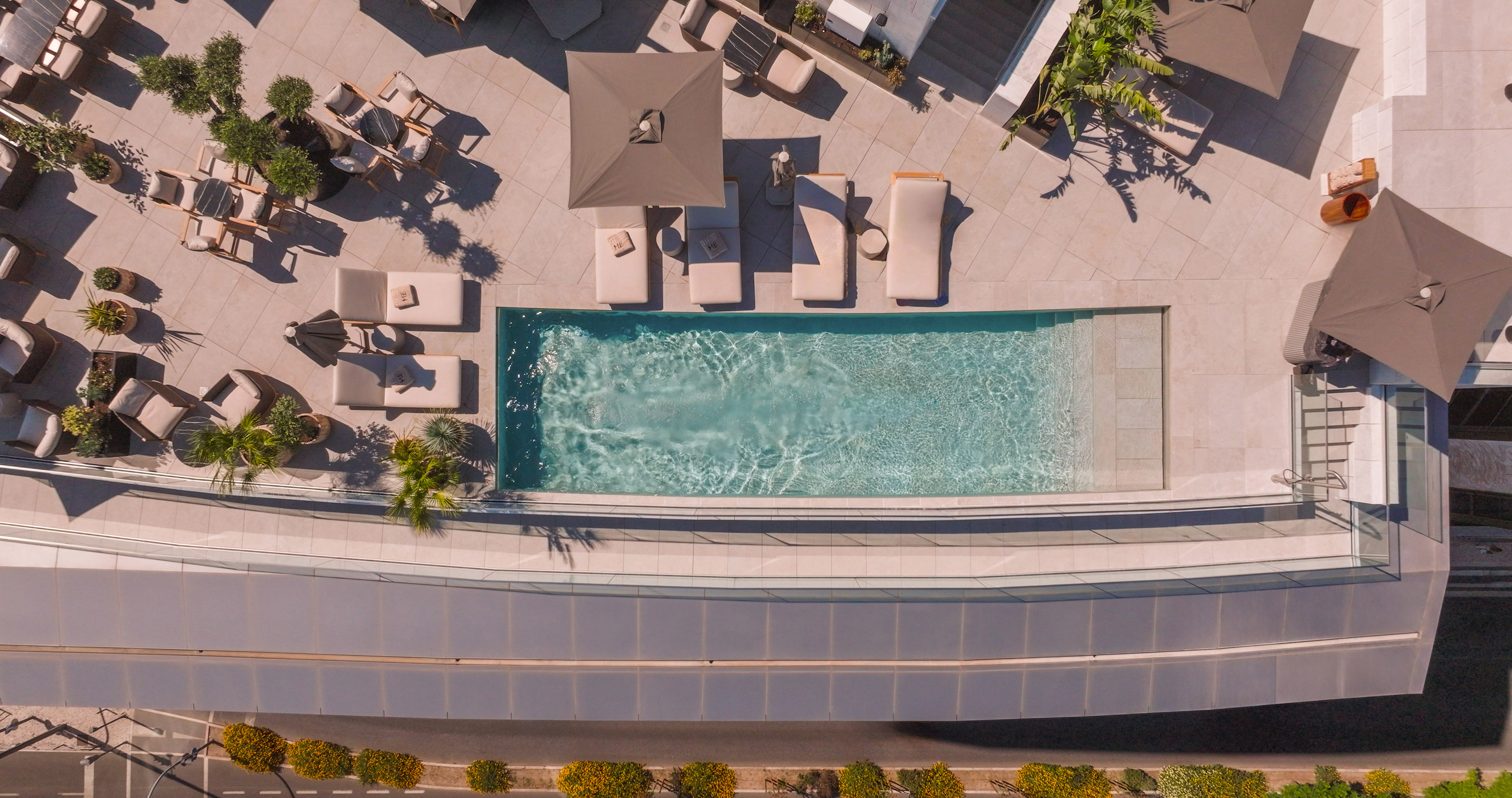Luxury hotel rooftop pool and terrace with sunbeds and umbrellas.