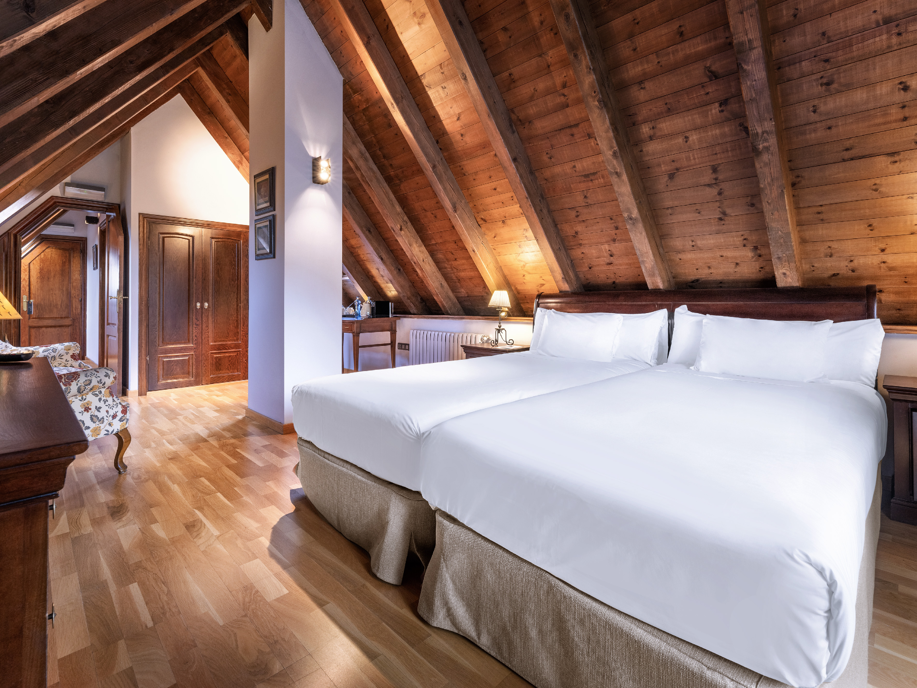 Rustic attic bedroom featuring two twin beds and a vaulted wooden ceiling.