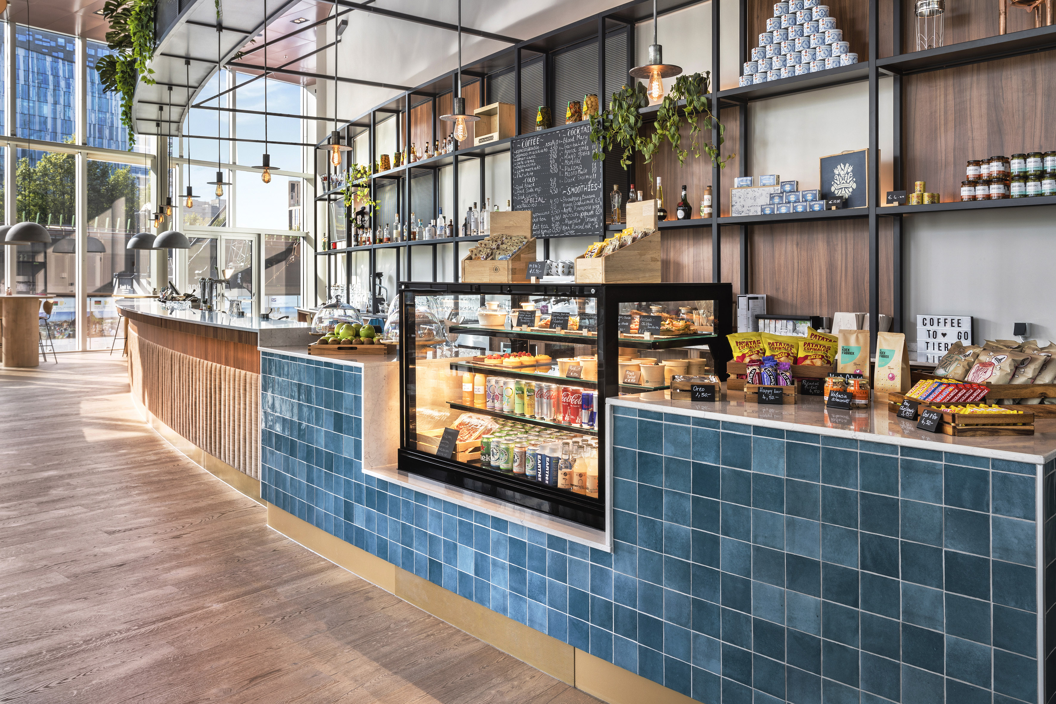Modern cafe interior with blue tiled counter, pastry display, and snacks.