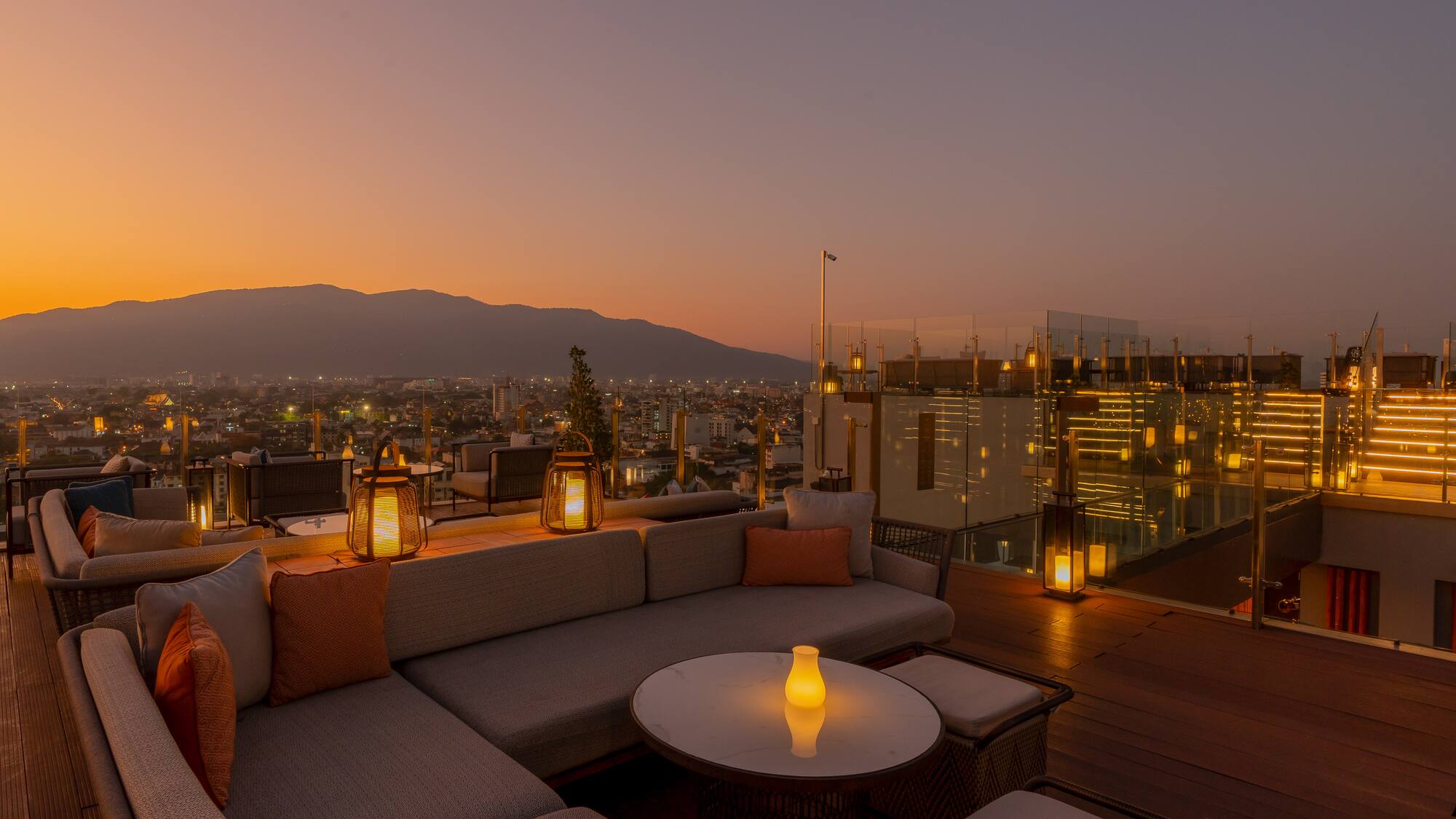 a rooftop patio with a view of a city and mountains