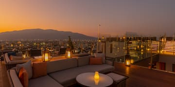a rooftop patio with a view of a city and mountains