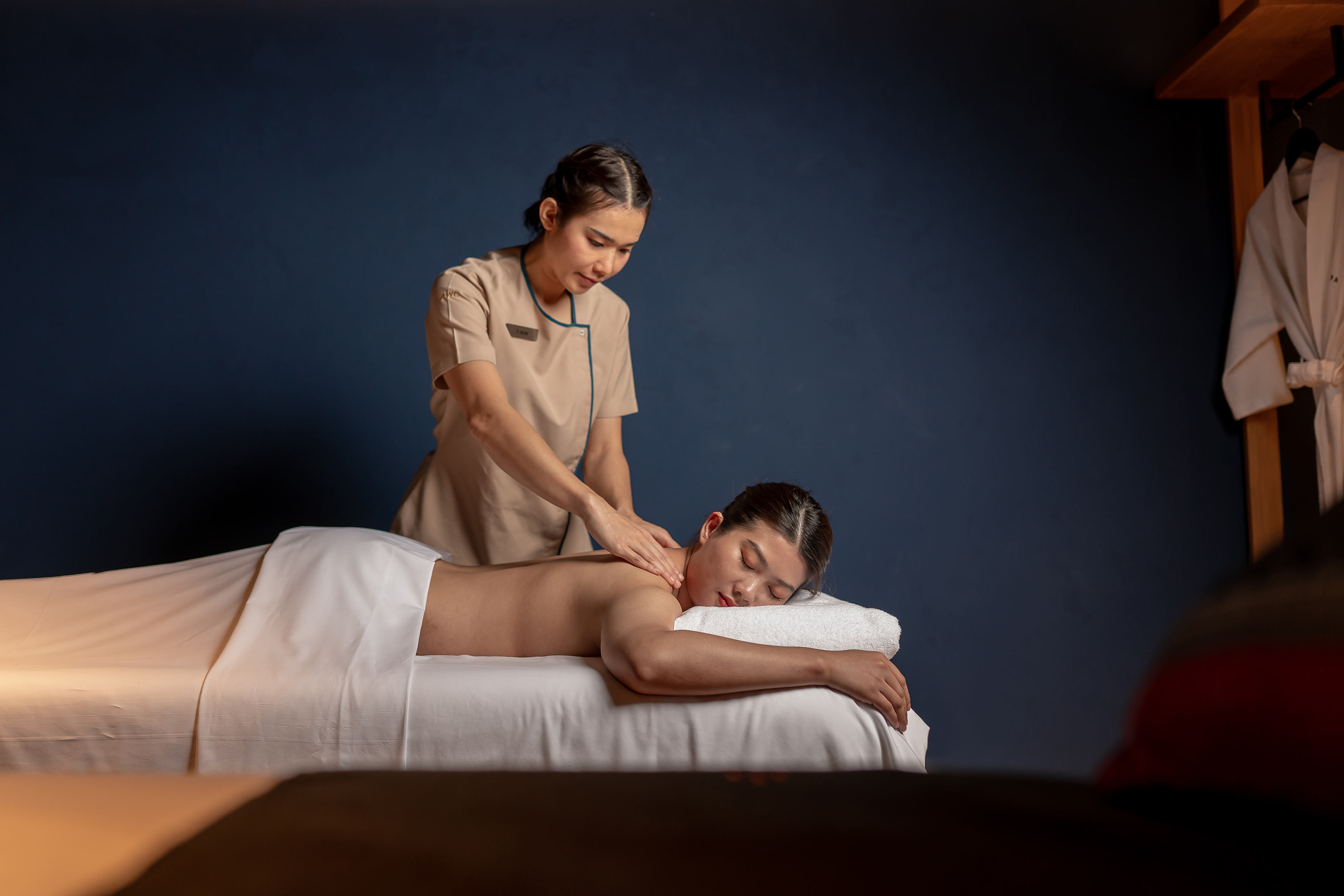 Massage therapist giving a relaxing back and shoulder massage to a woman at a spa.