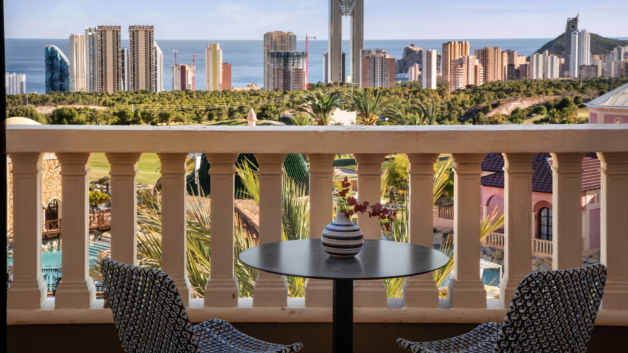 a table and chairs on a balcony overlooking a city
