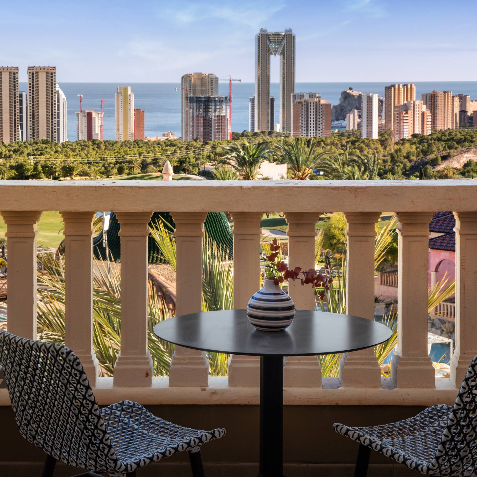 a table and chairs on a balcony overlooking a city