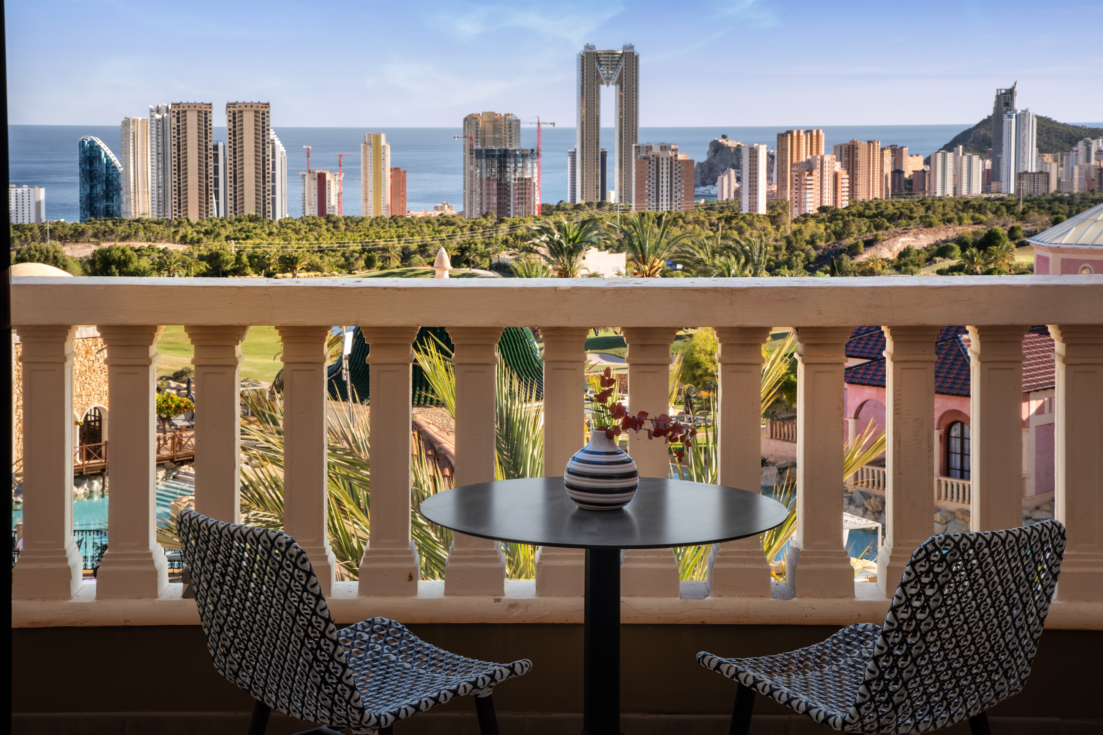Benidorm resort balcony with city skyline, ocean, and golf course view.