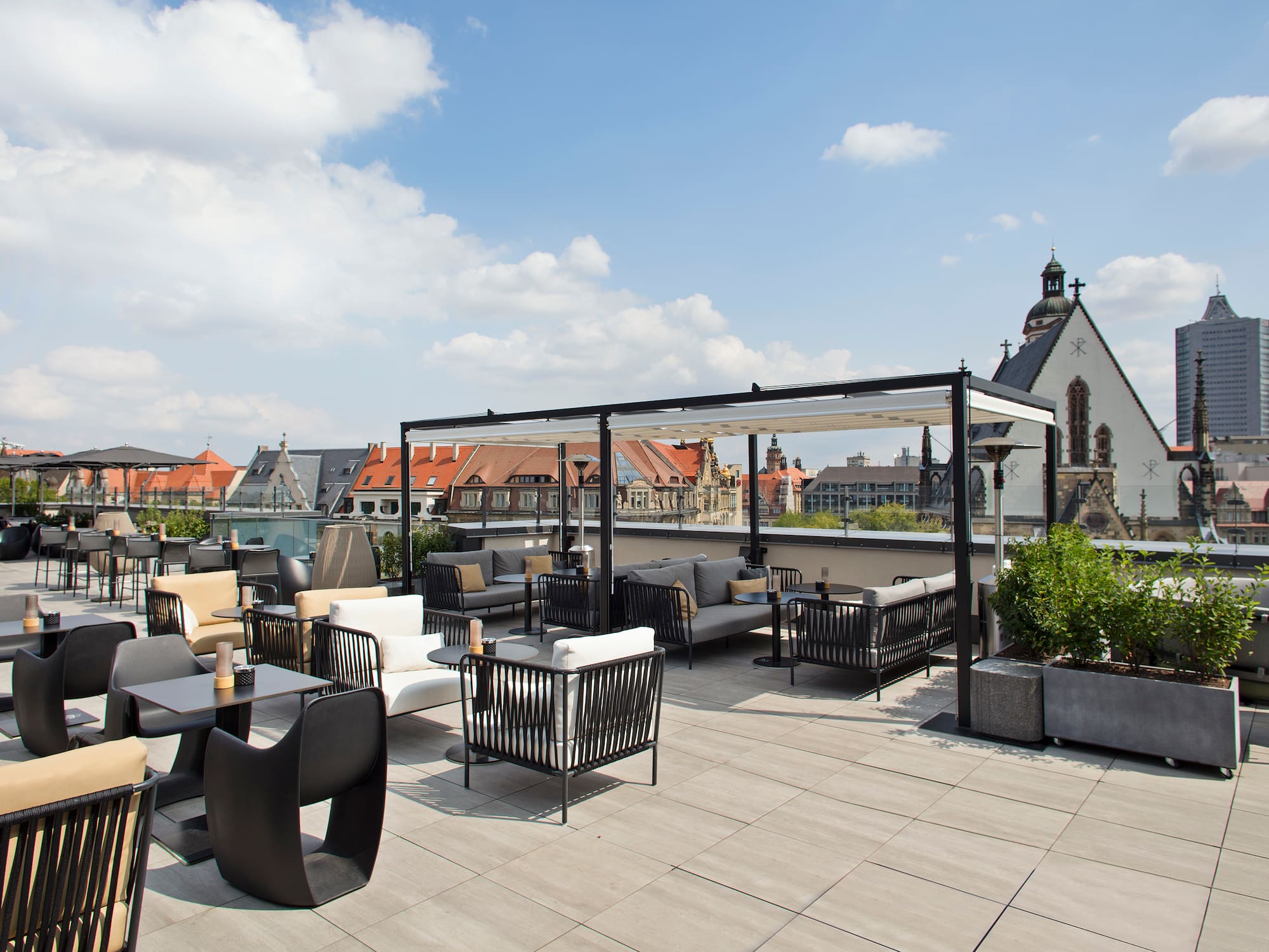 Modern rooftop terrace with outdoor lounge seating and Leipzig city view.
