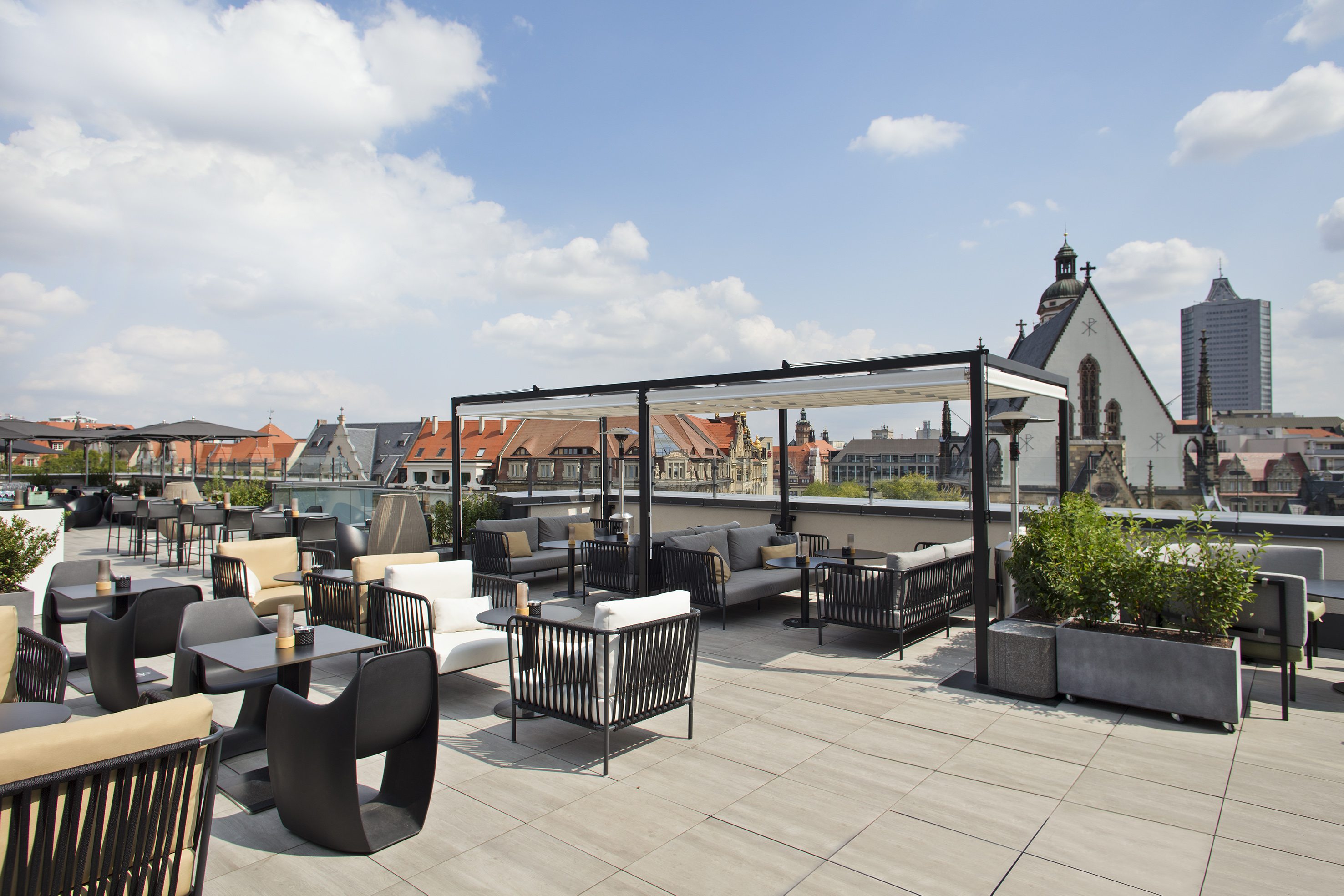 Modern rooftop terrace with outdoor lounge seating and Leipzig city view.