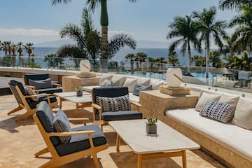 a patio with chairs and tables and palm trees