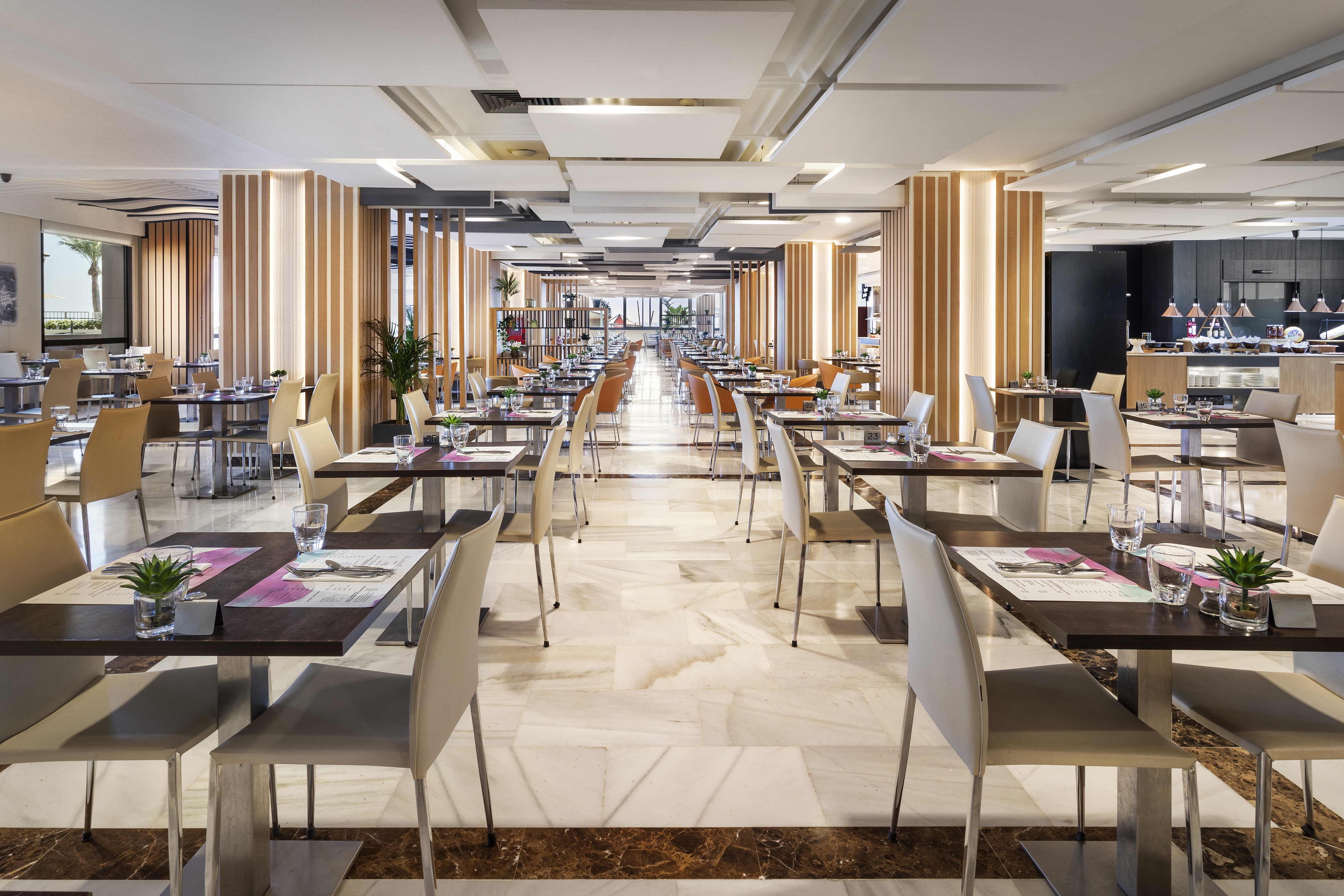 Modern spacious hotel restaurant dining room with set tables and buffet.
