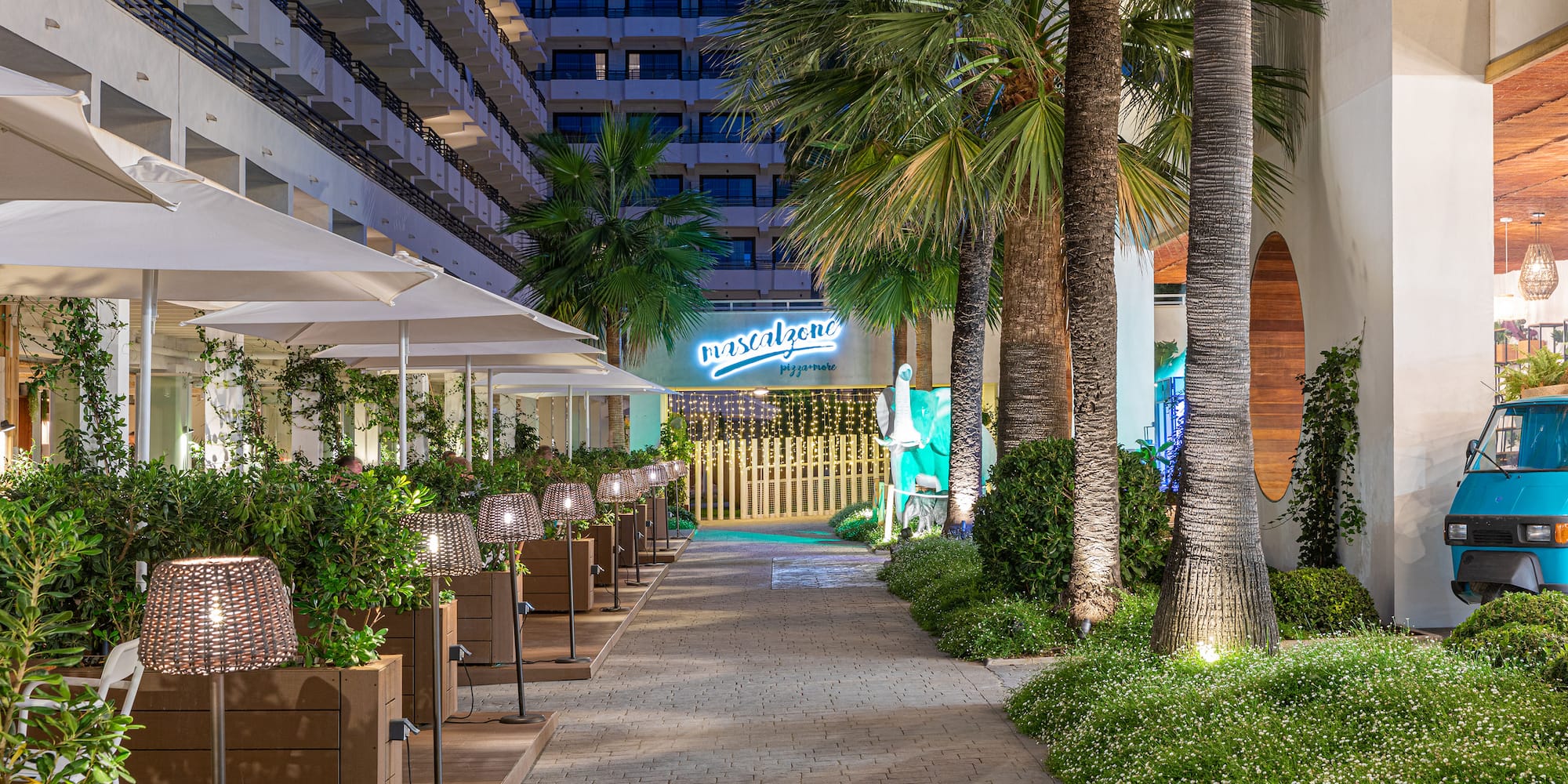 a walkway with palm trees and a building
