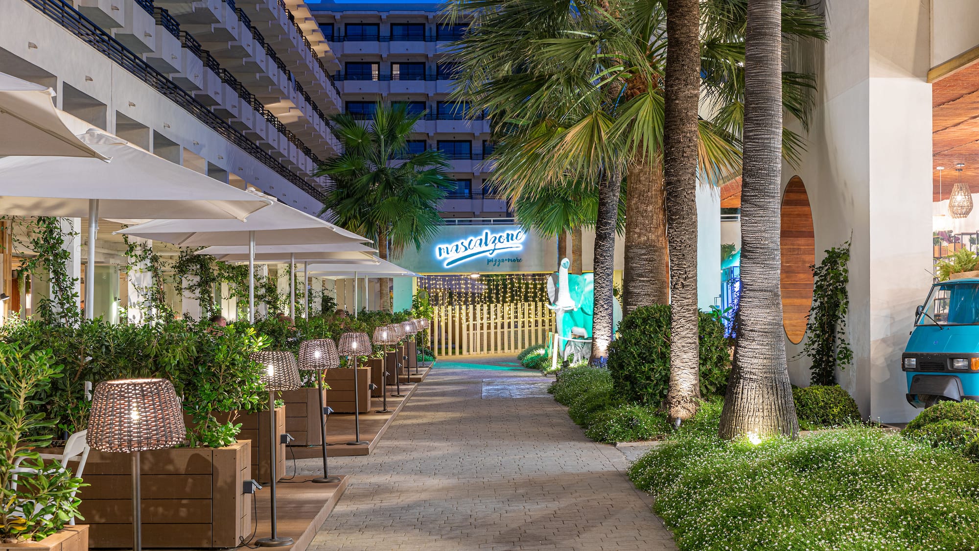a walkway with palm trees and a building