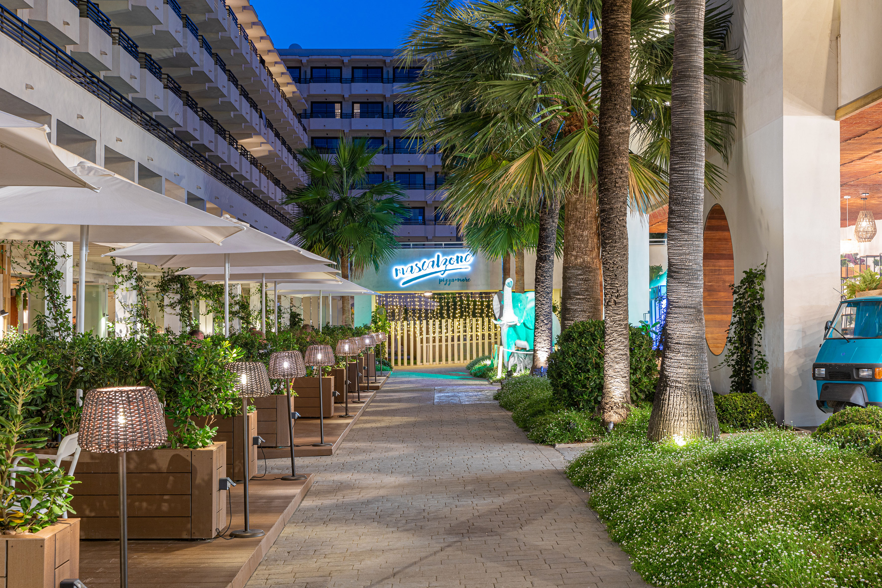 Hotel Mascalzone restaurant patio with palm trees, evening outdoor dining.