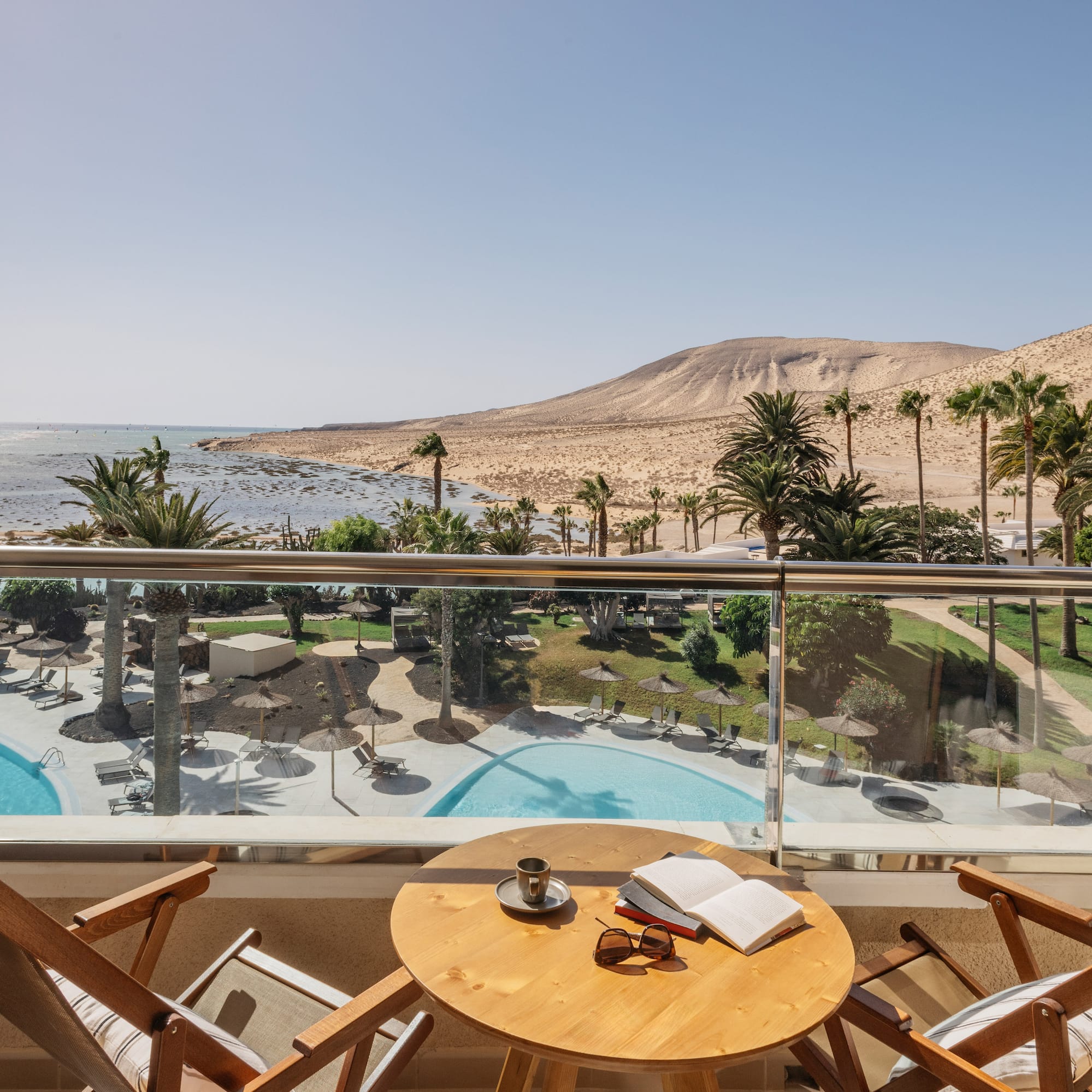a table and chairs on a balcony overlooking a pool and mountains