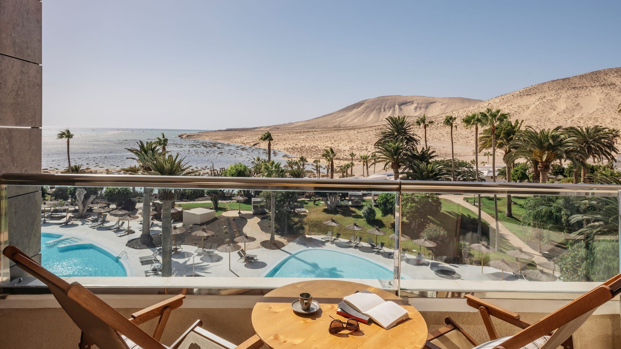 a table and chairs on a balcony overlooking a pool and mountains