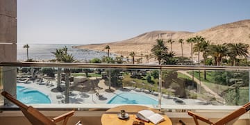 a table and chairs on a balcony overlooking a pool and mountains