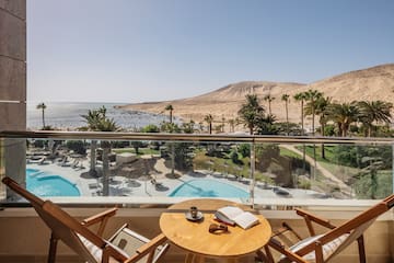 a table and chairs on a balcony overlooking a pool and mountains
