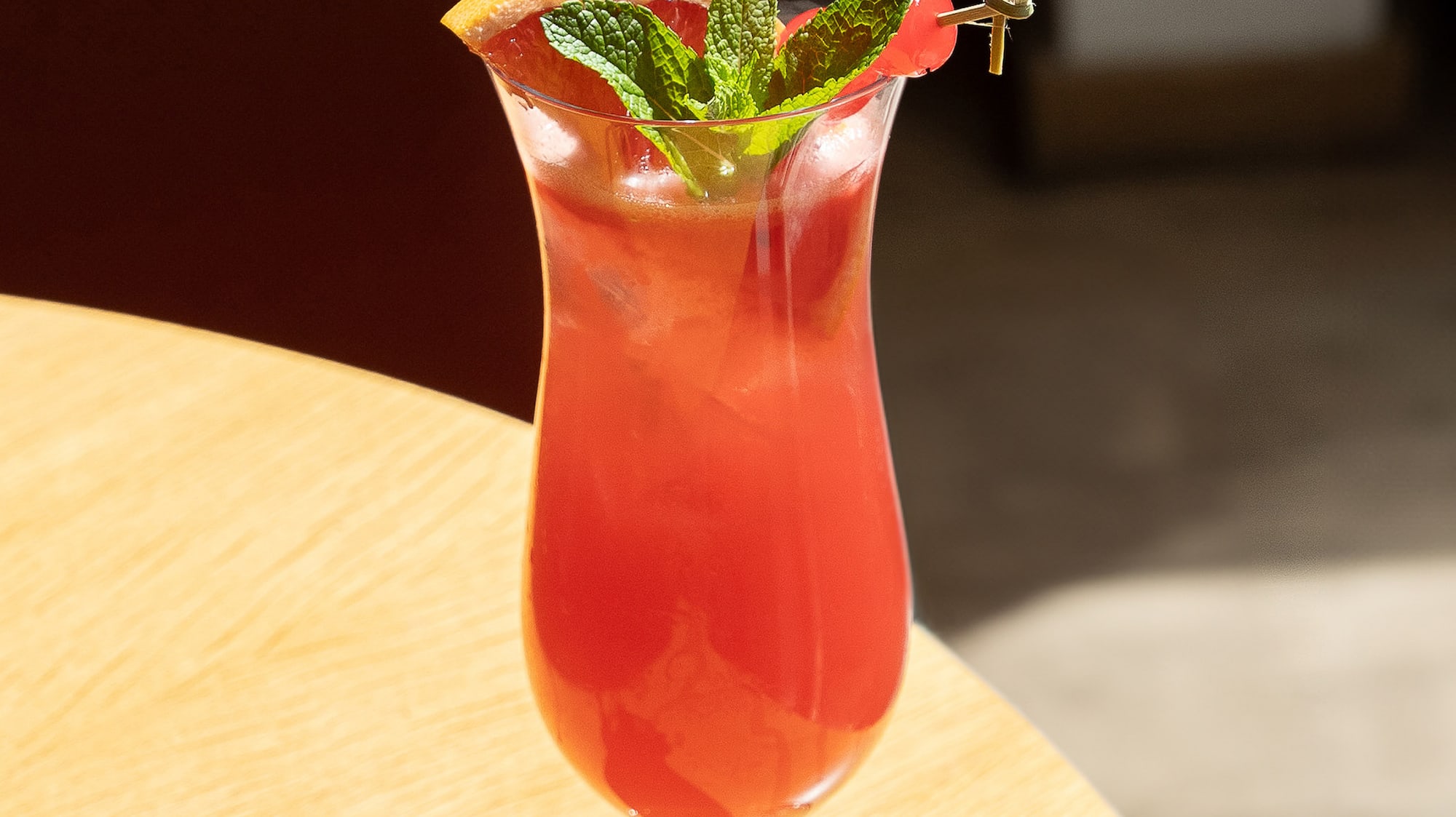 a glass of red drink with a leafy garnish