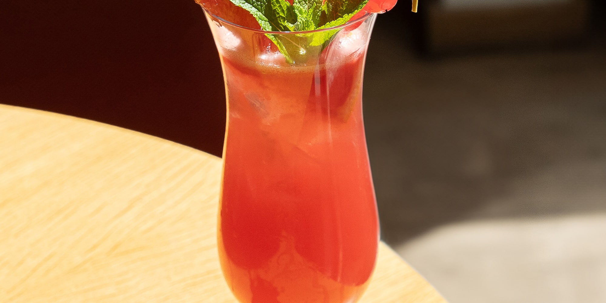a glass of red drink with a leafy garnish