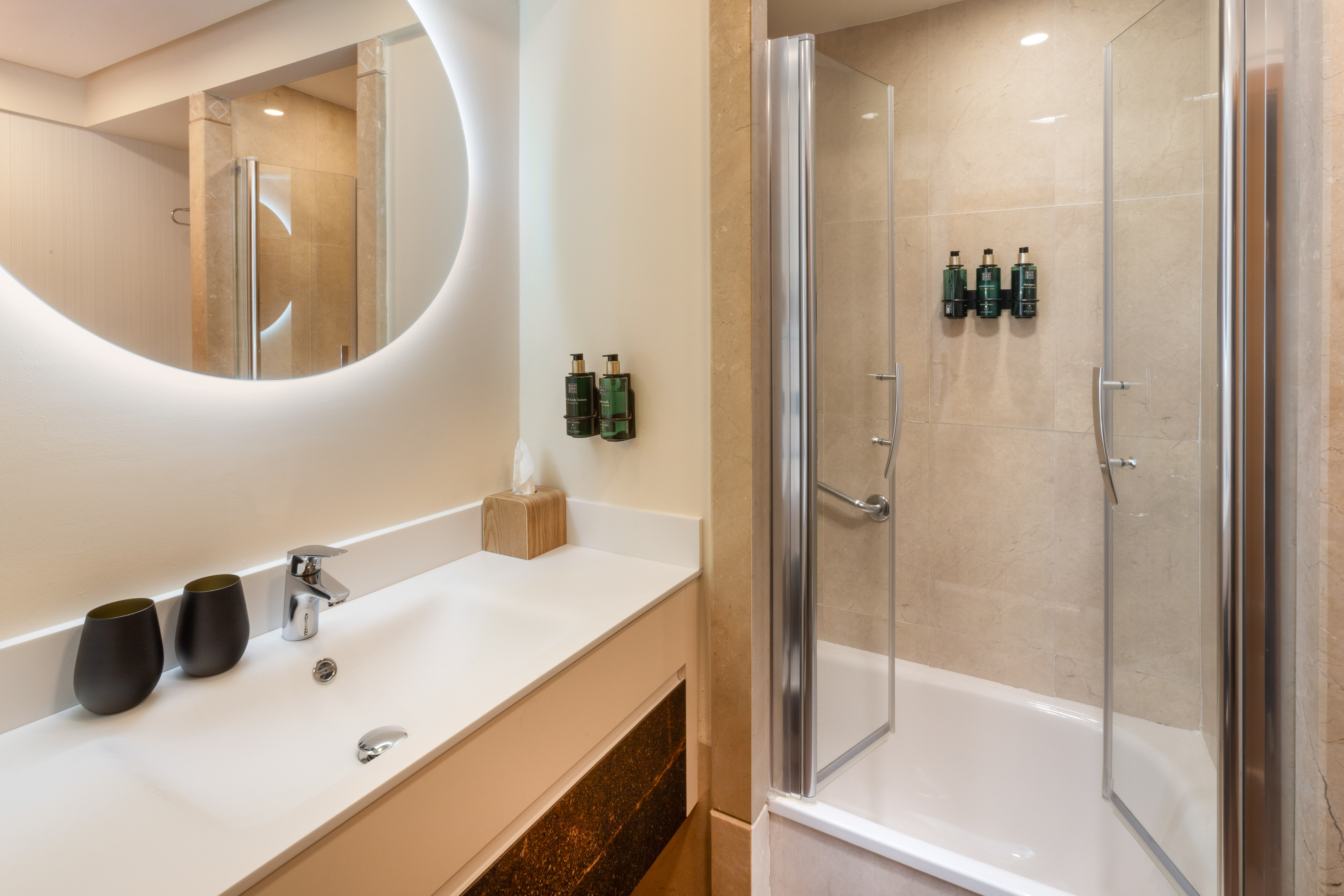 Modern hotel bathroom with illuminated mirror, sink, and shower-bathtub.