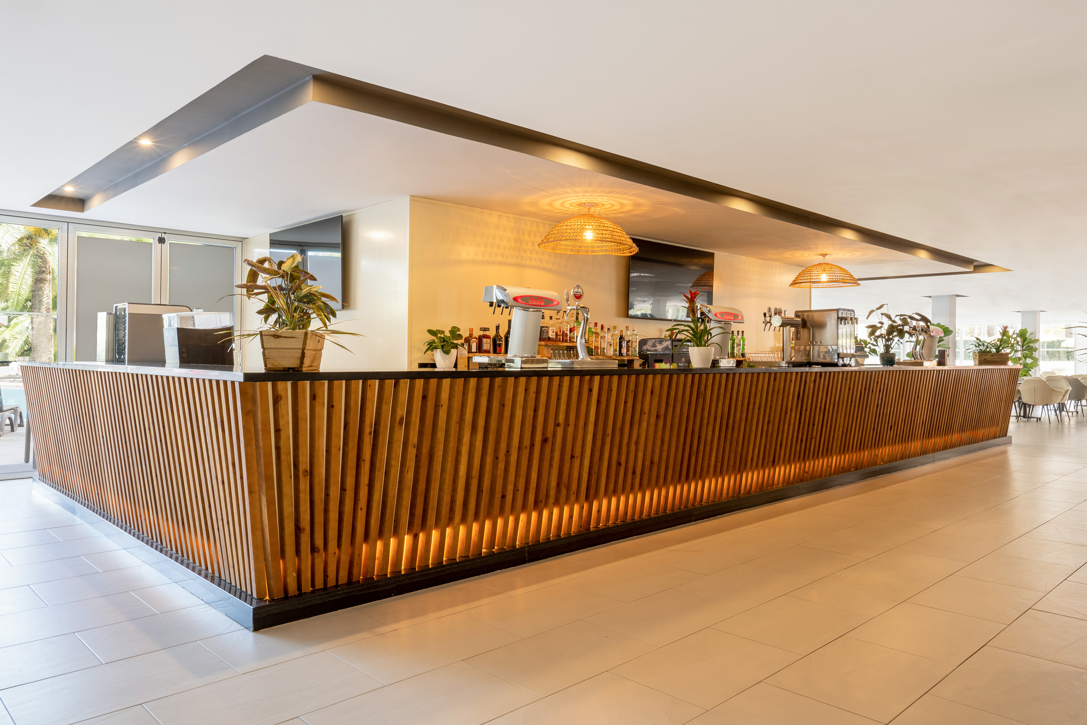 Modern wooden slat bar counter with warm lighting in a hotel lounge.
