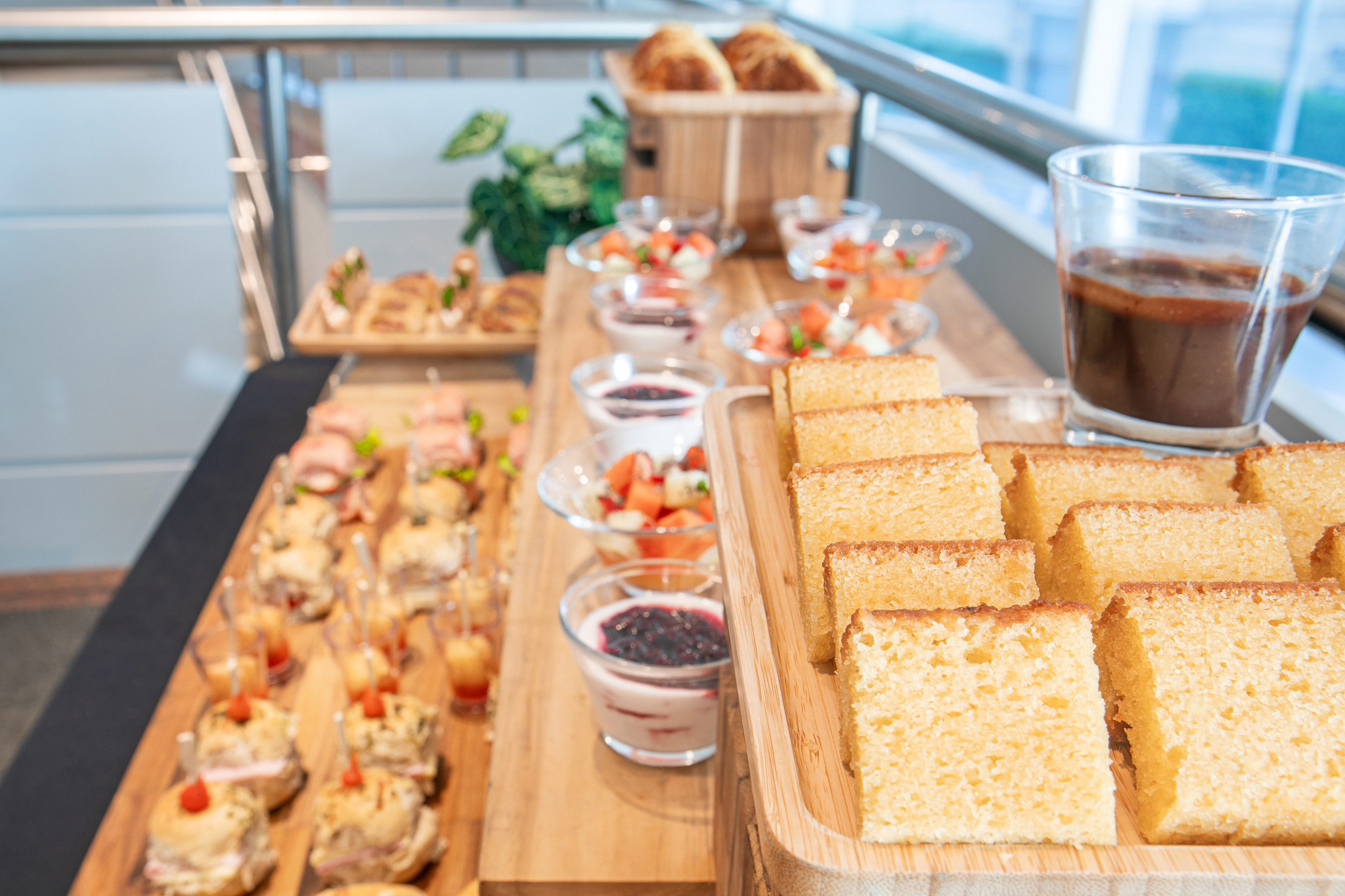 Assorted buffet with golden cake slices, mini sandwiches, fruit, and yogurt.