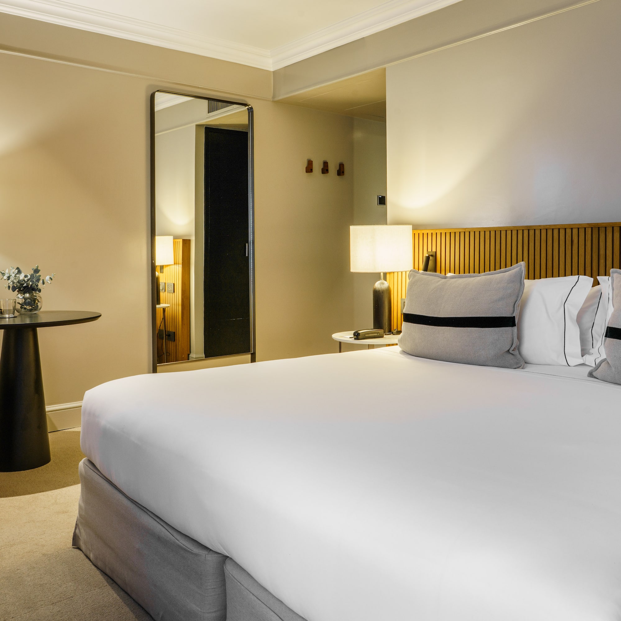 a bed with white sheets and a table with lamps