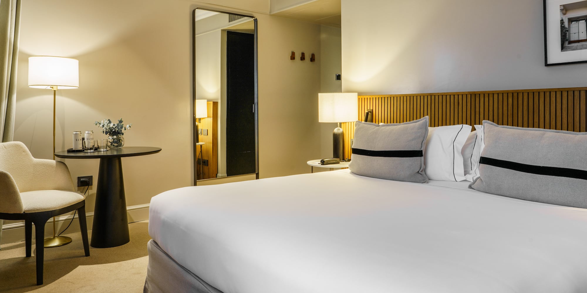 a bed with white sheets and a table with lamps