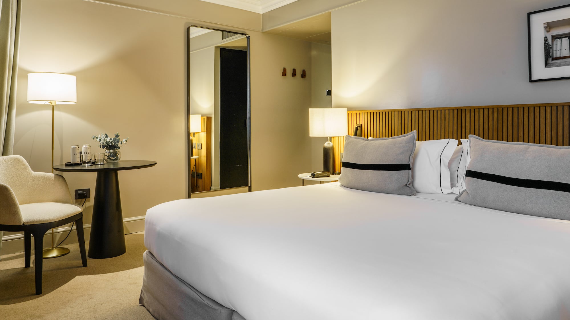 a bed with white sheets and a table with lamps