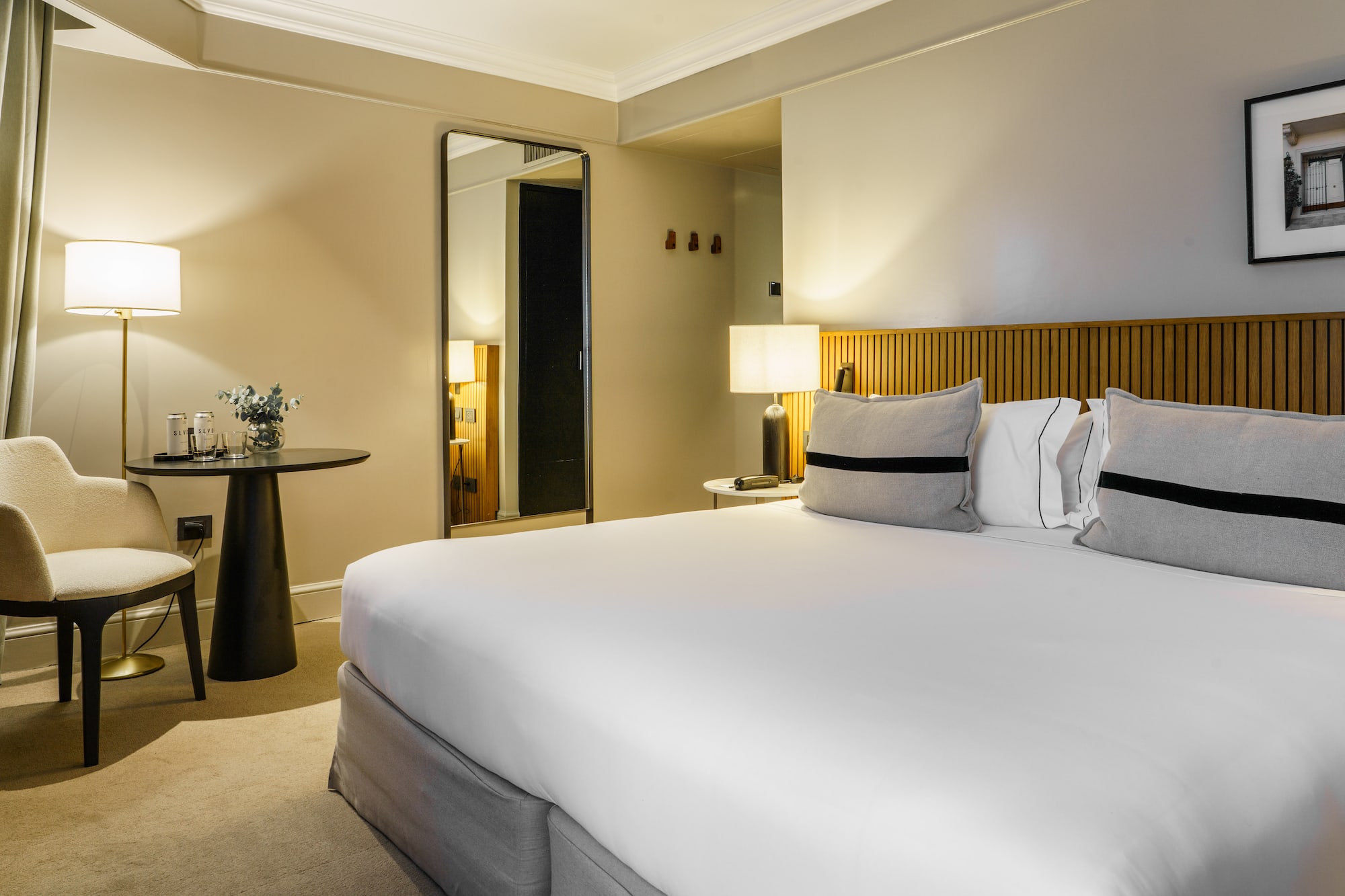 a bed with white sheets and a table with lamps