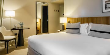 a bed with white sheets and a table with lamps