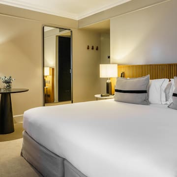 a bed with white sheets and a table with lamps