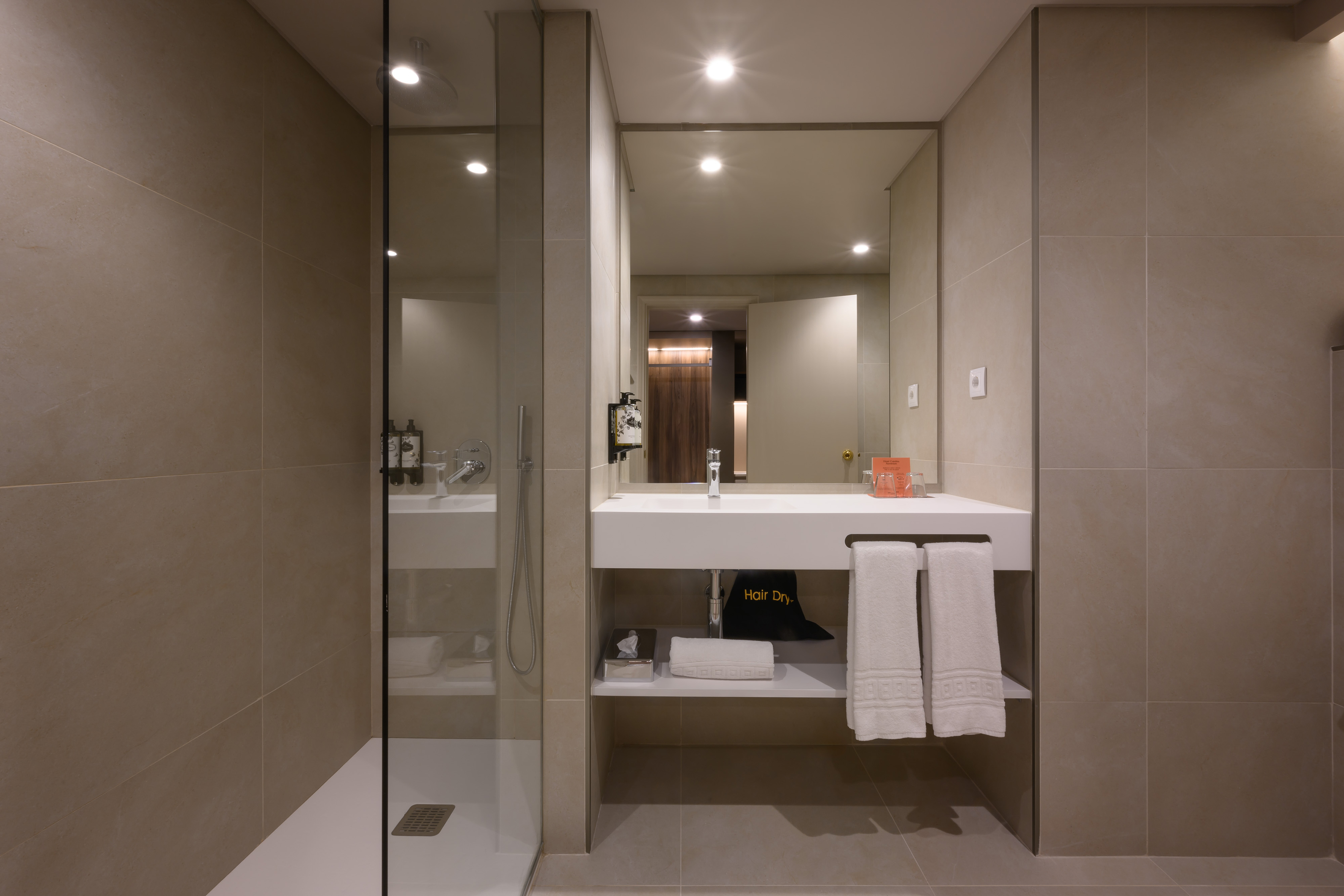 Modern hotel bathroom with walk-in shower, floating vanity, and fresh towels.