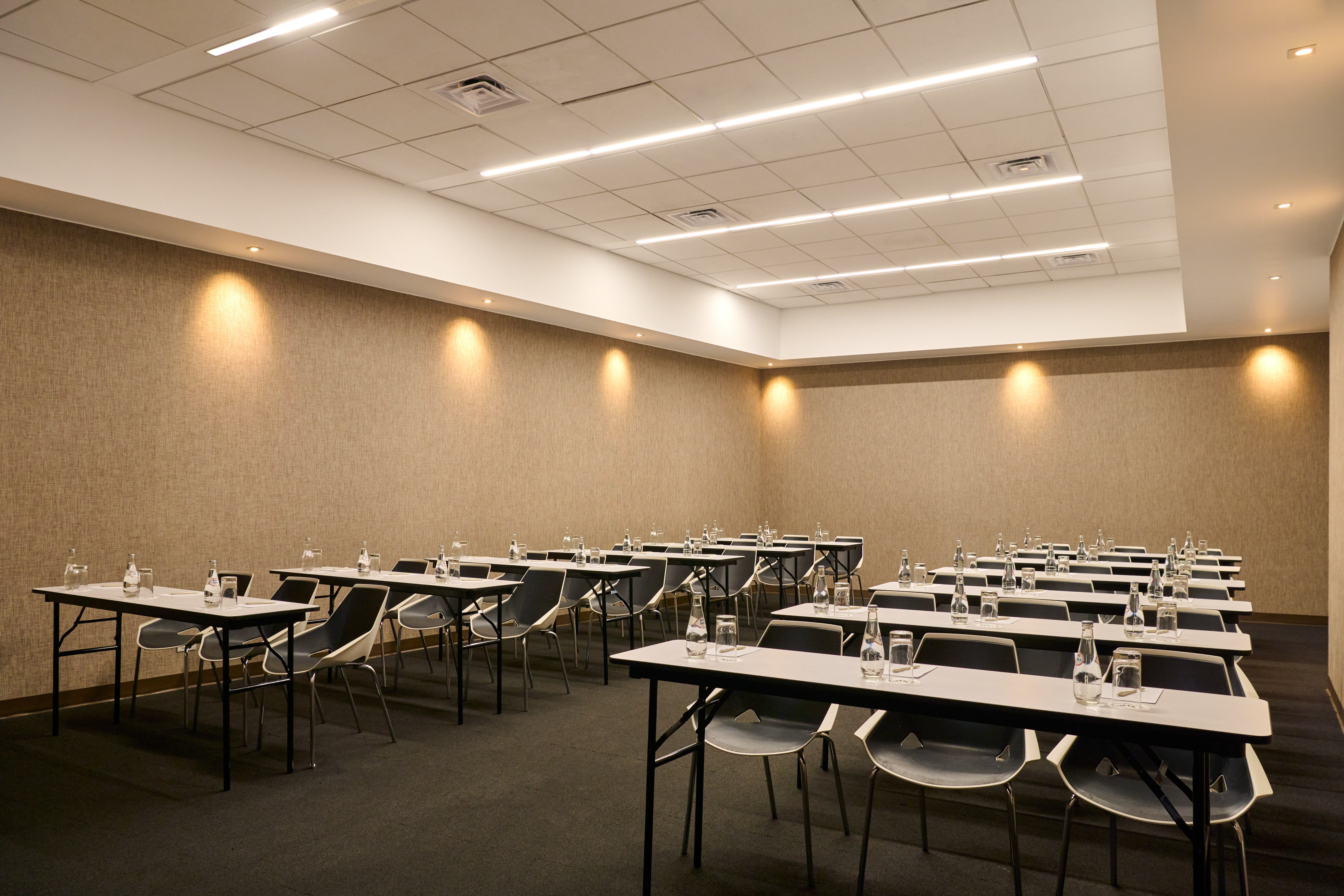 Modern conference room in classroom setup with water bottles and LED lighting.