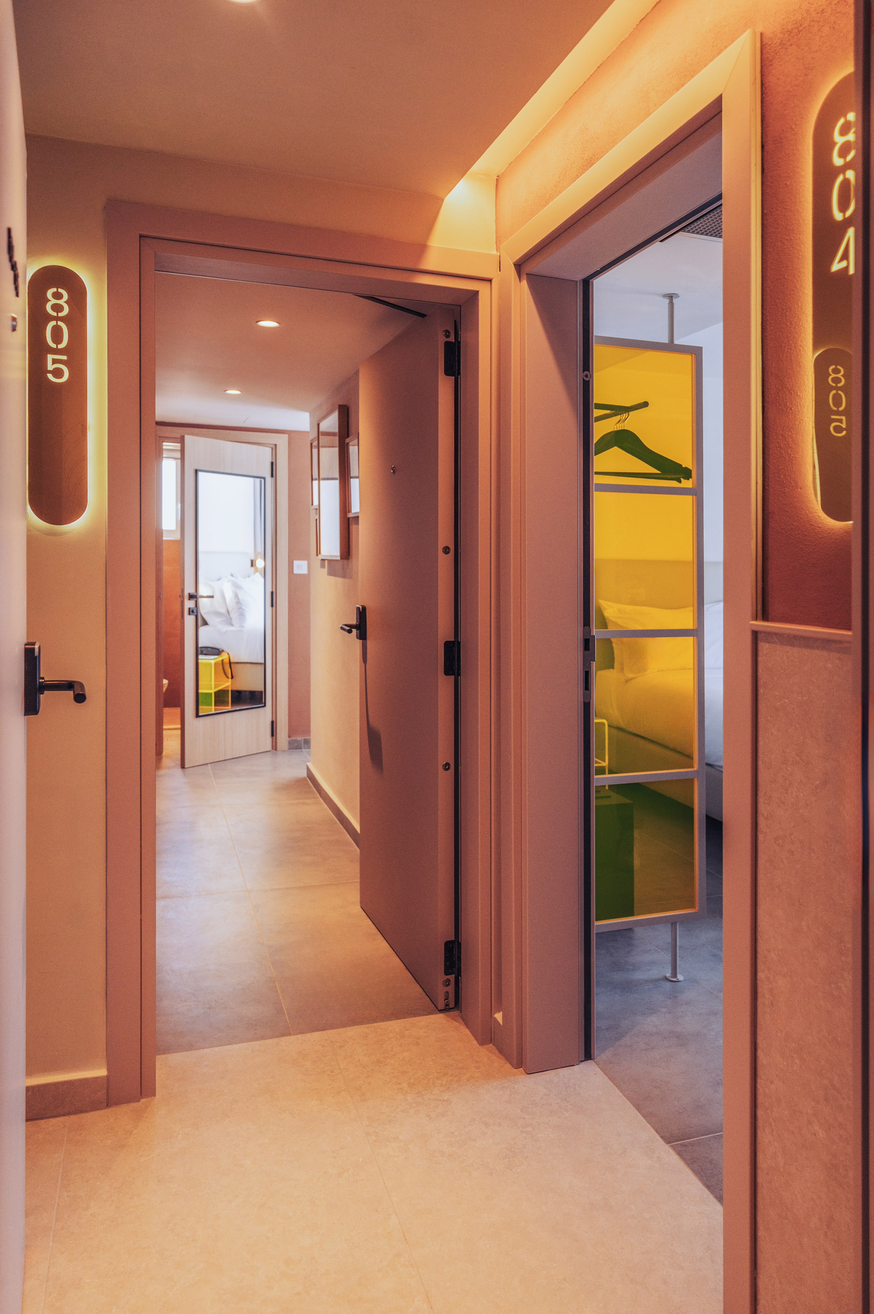Boutique hotel hallway with open doors to rooms 805, 804 and warm lighting.