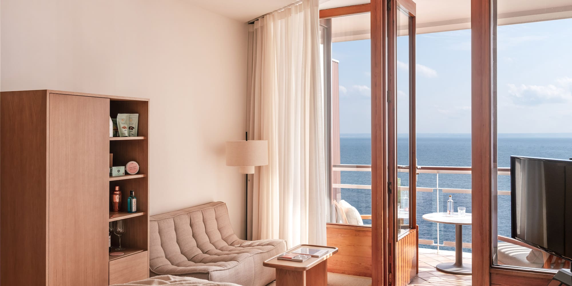 a room with a bed and a couch and a table with a view of the ocean