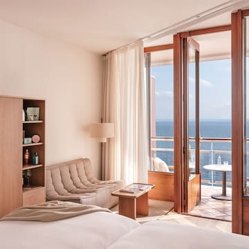 a room with a bed and a couch and a table with a view of the ocean