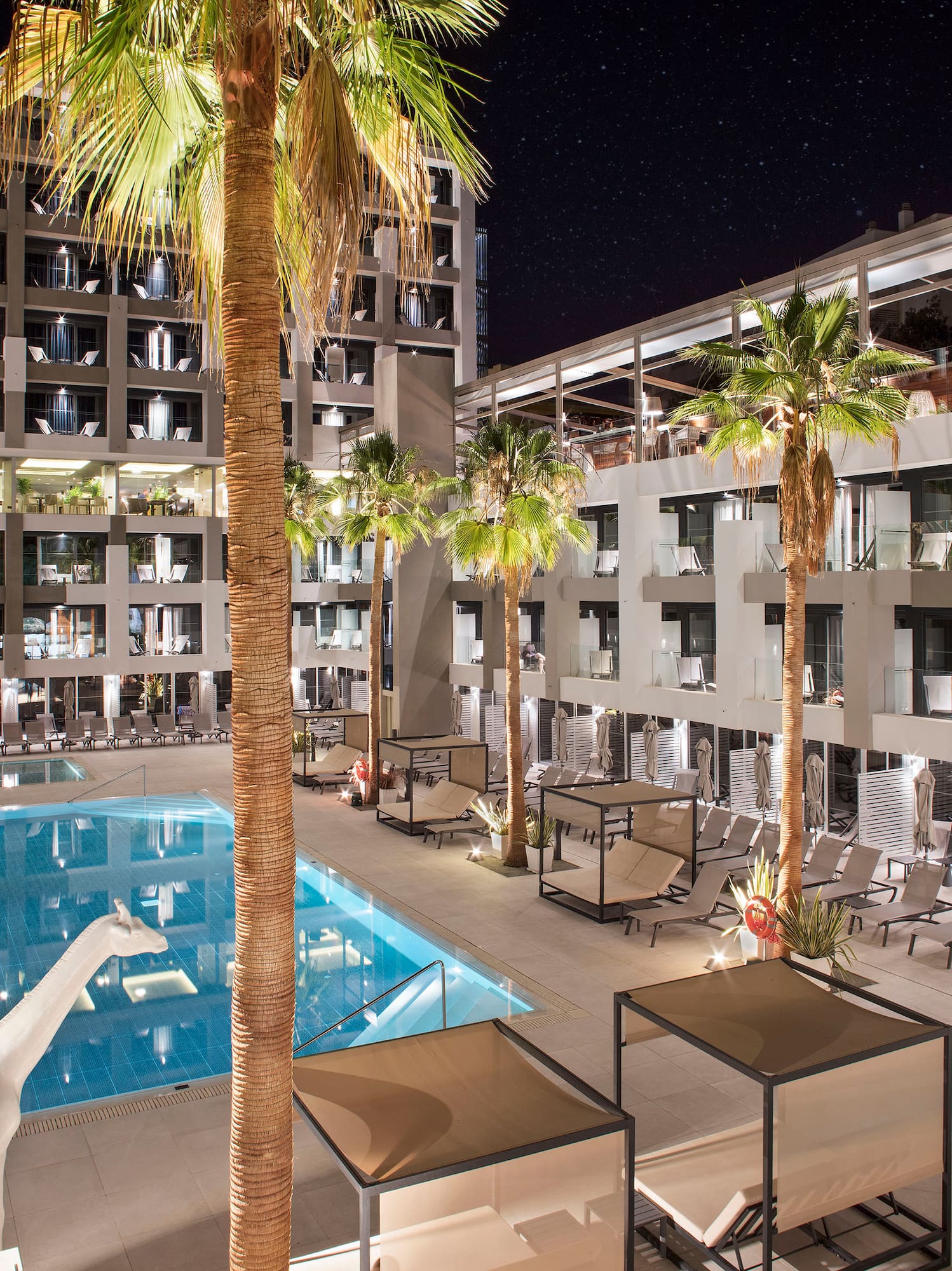 a swimming pool and palm trees in front of a building